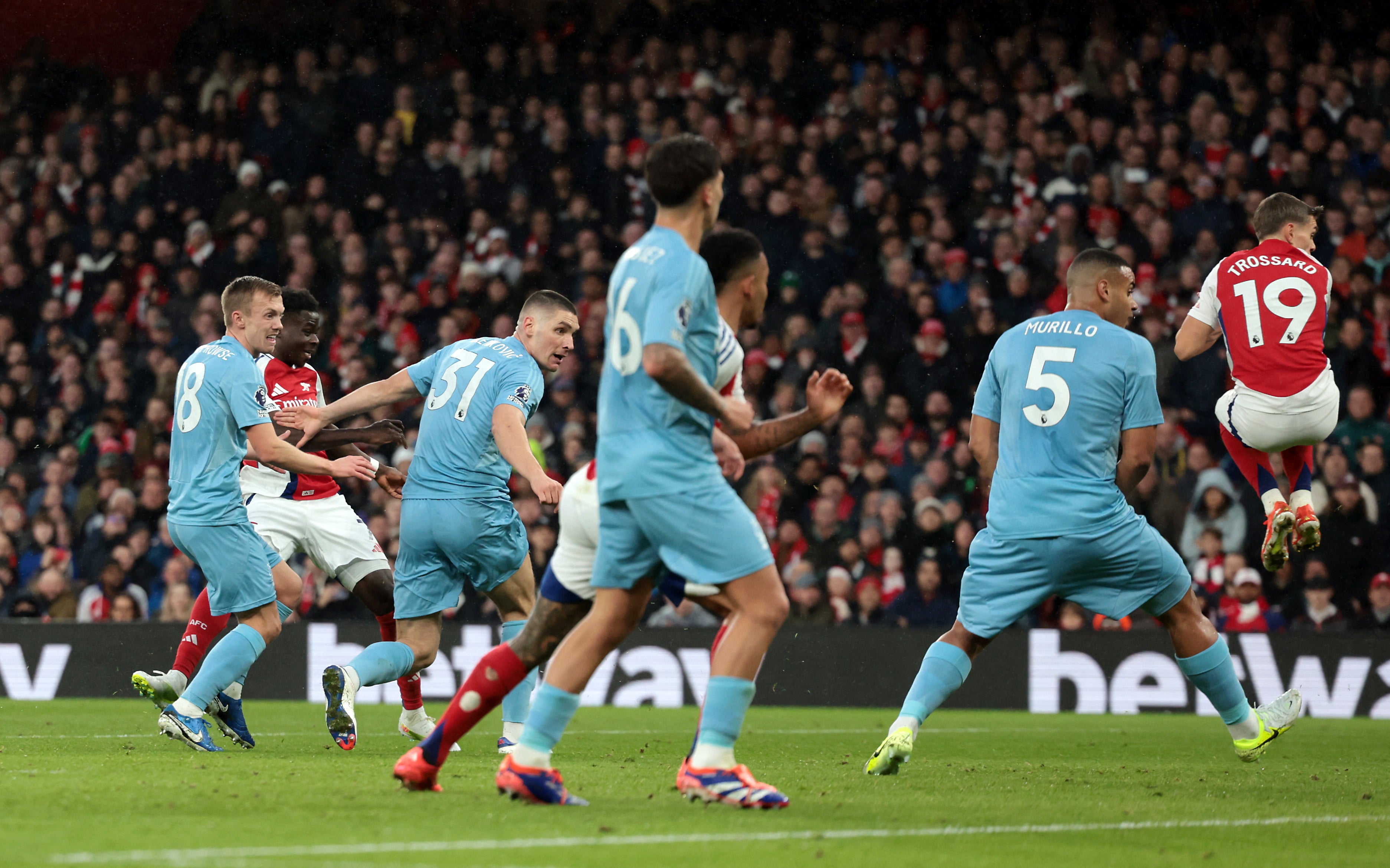 Leandro Trossard (19) takes evasive action as Saka’s shot finds the net