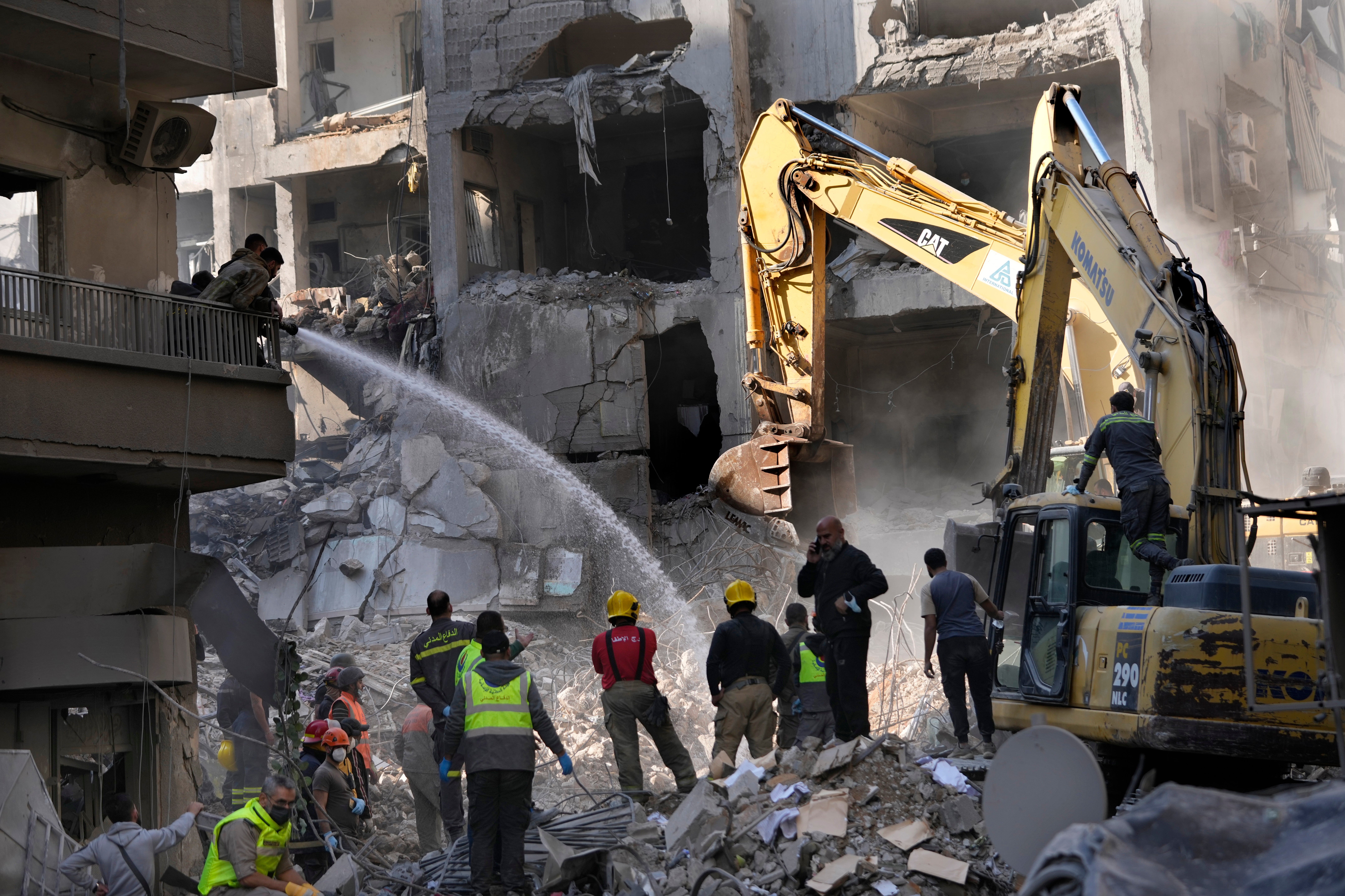 Firefighters spray water to reduce the dust for the rescuers who search for victims at the site of an Israeli airstrike that hit central Beirut, Lebanon, on Saturday