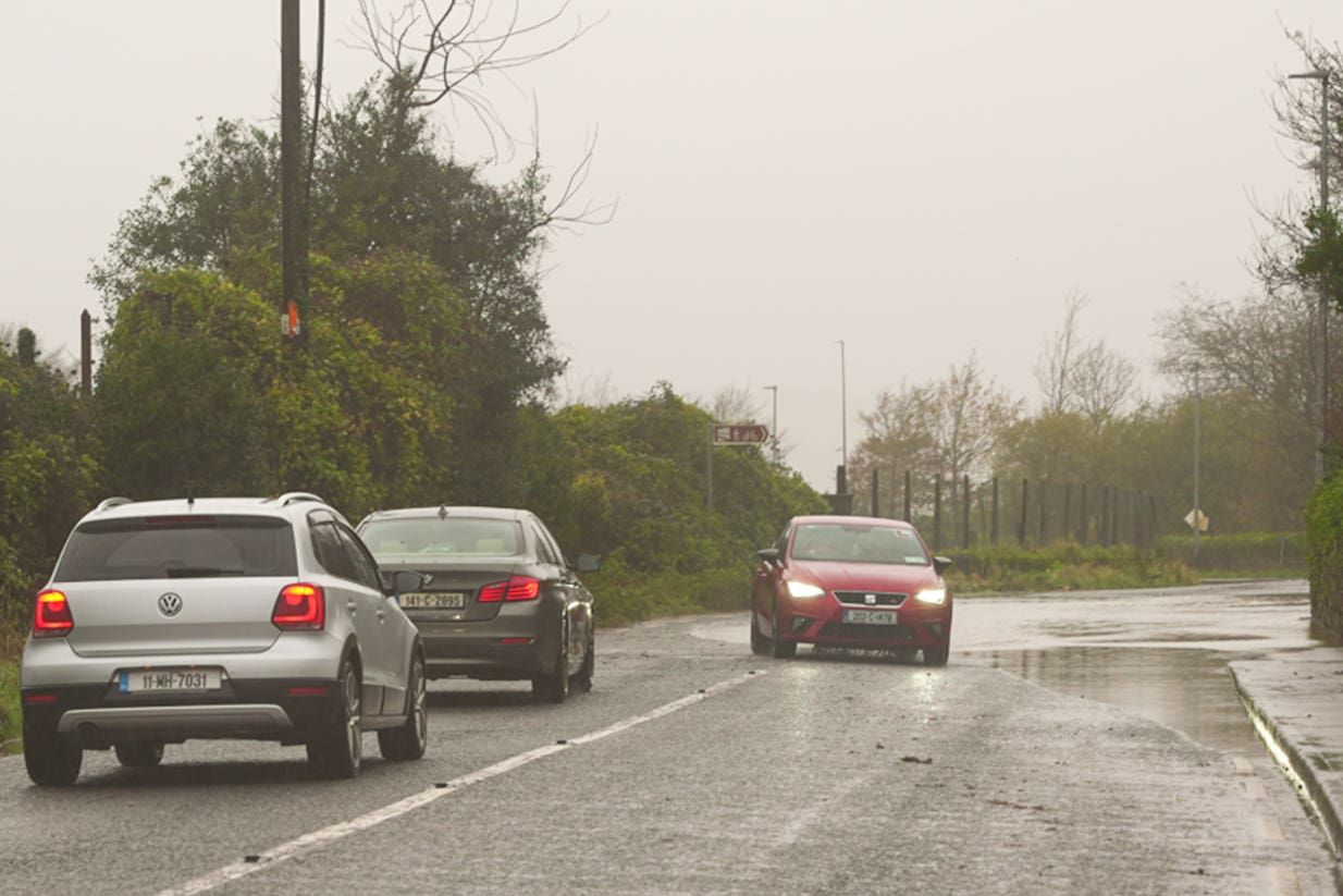 A car is driven past a flooded road at Passage West, Co Cork (Noel Sweeney/PA)