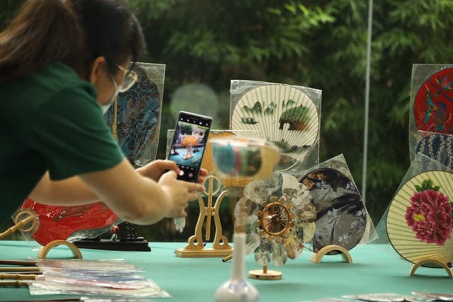 <p>A visitor takes photos of Chinese tuanshan fans exhibited in May in Guilin, Guangxi Zhuang autonomous region</p>