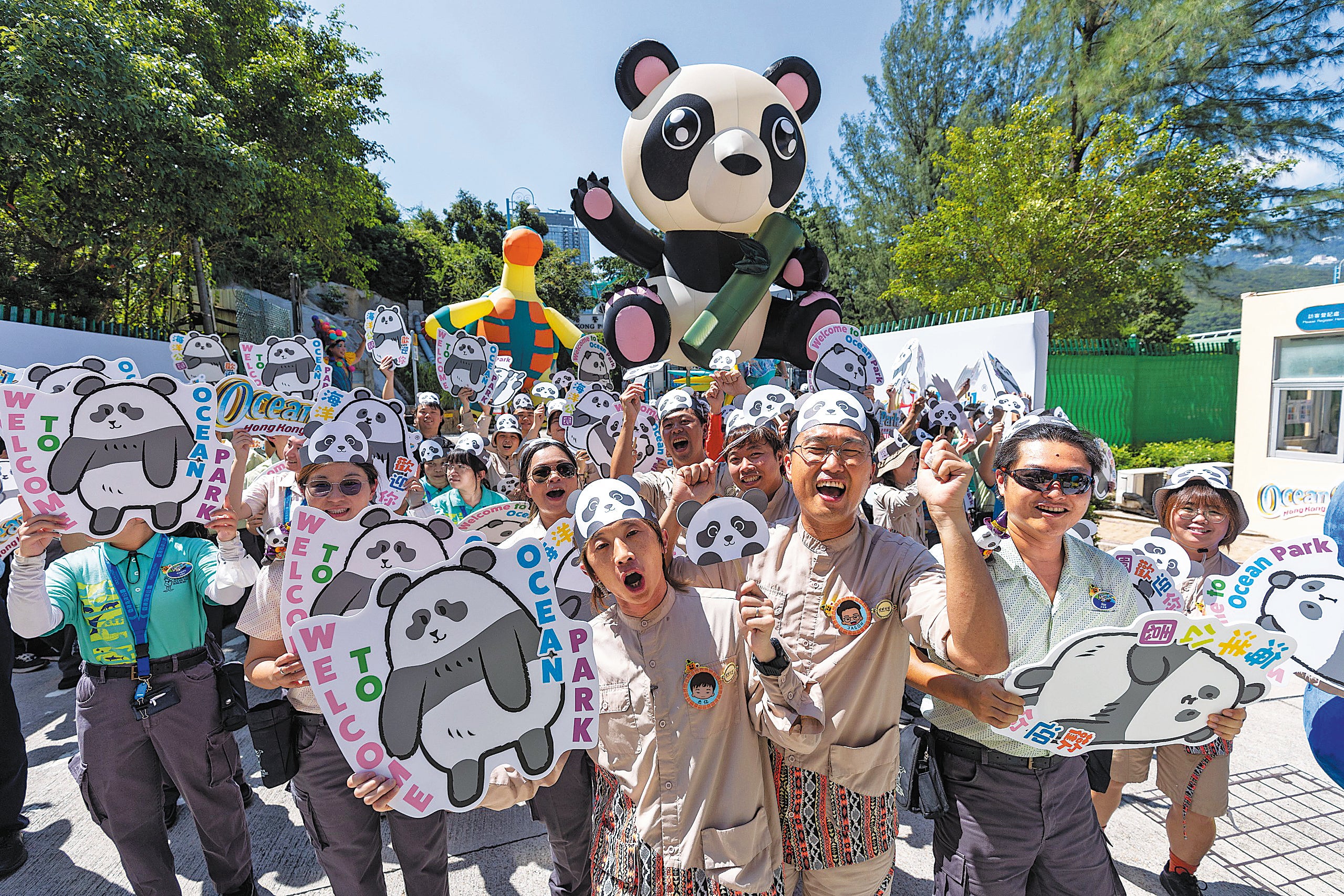 Ocean Park staff hold up signs and wear panda headgear to welcome An An and Ke Ke on 26 September