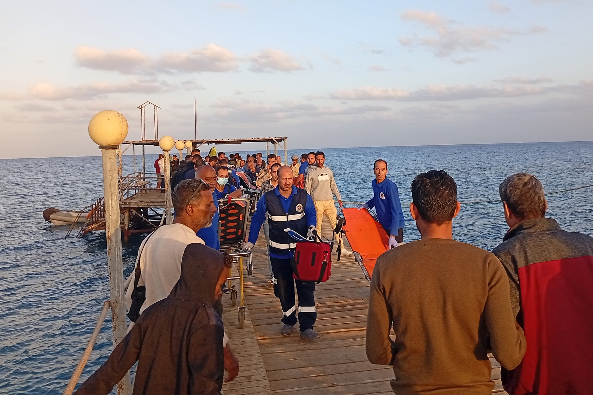 Medics and people wait for possible survivors after a the yacht sank in the Red Sea on Monday