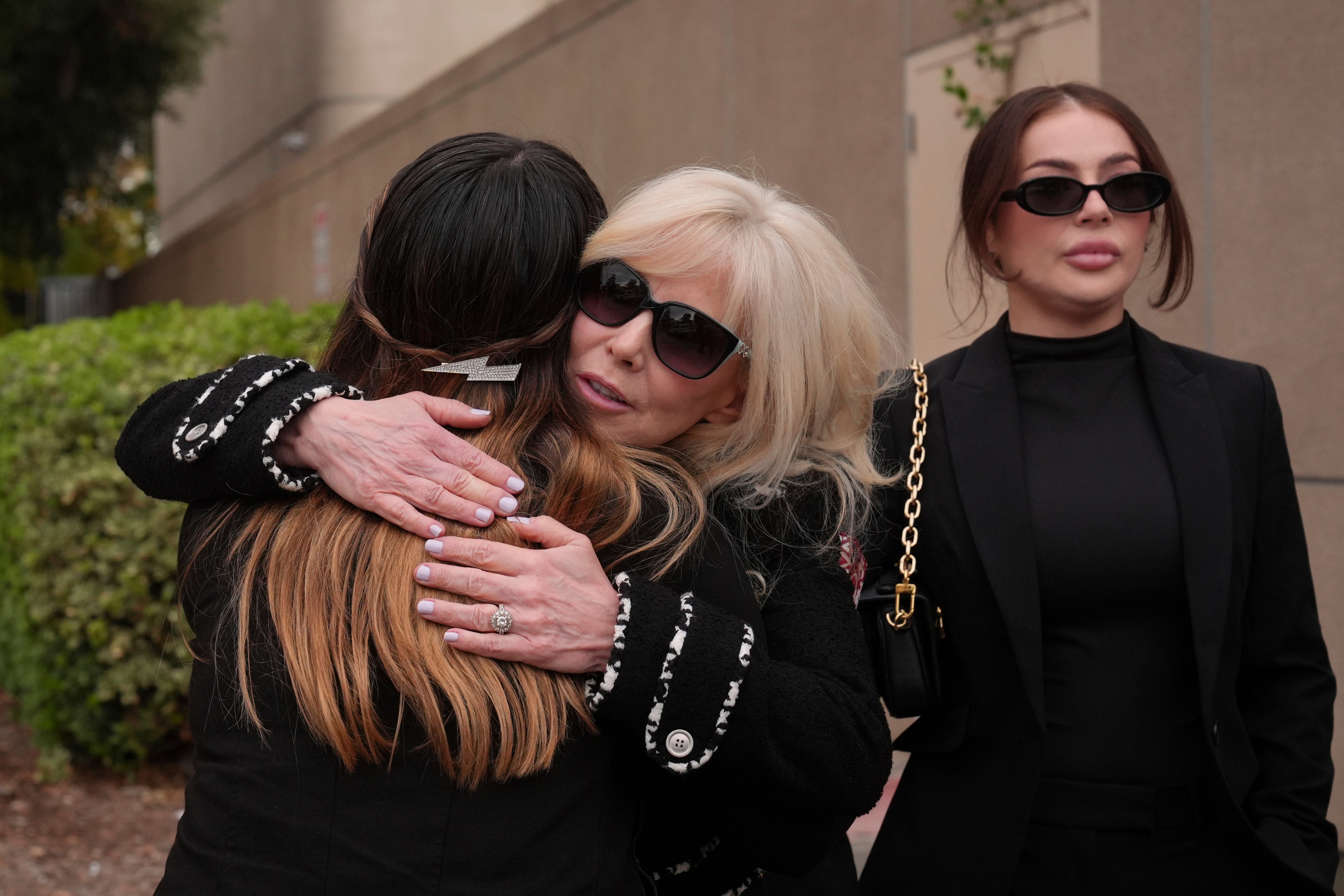 Tammi Menendez, center, the wife of Eric Menendez, is hugged by an unidentified woman as she leaves a courthouse on Monday