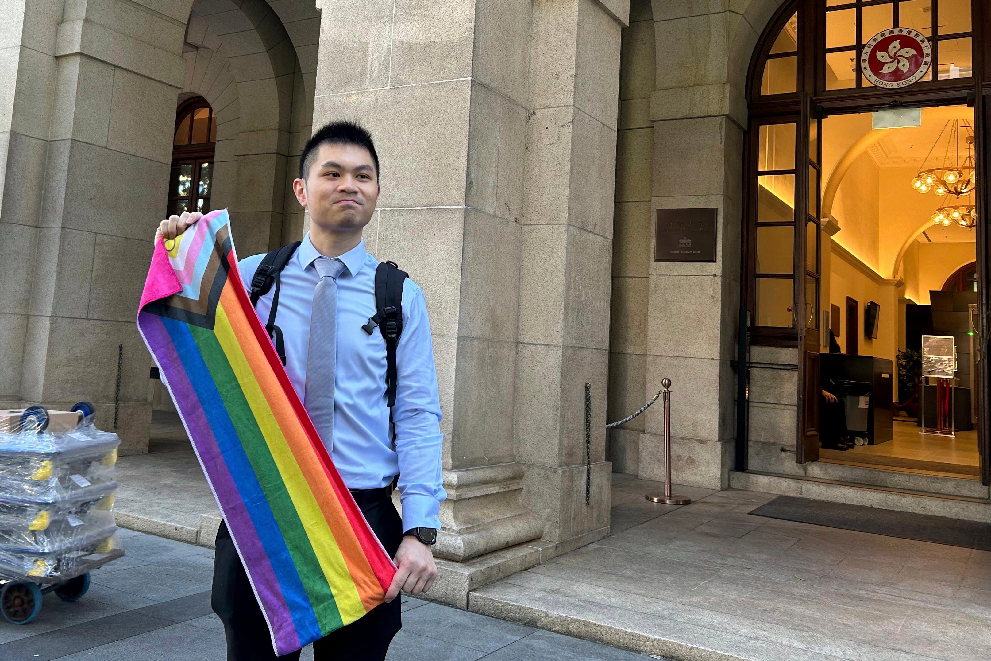 Nick Infinger, who won a years-long legal battle over the differential treatment facing same-sex couples, holds up a rainbow banner after speaking to media members outside Hong Kong’s top court on Tuesday, 26 Nov 2024