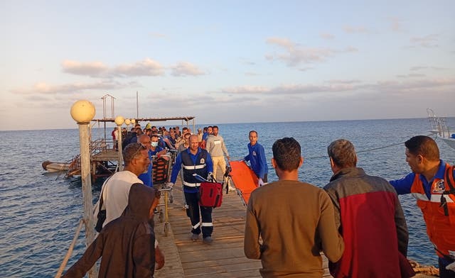 <p> Medics and people wait for possible survivors after a boat sank at a harbour in Marsa Alam</p>