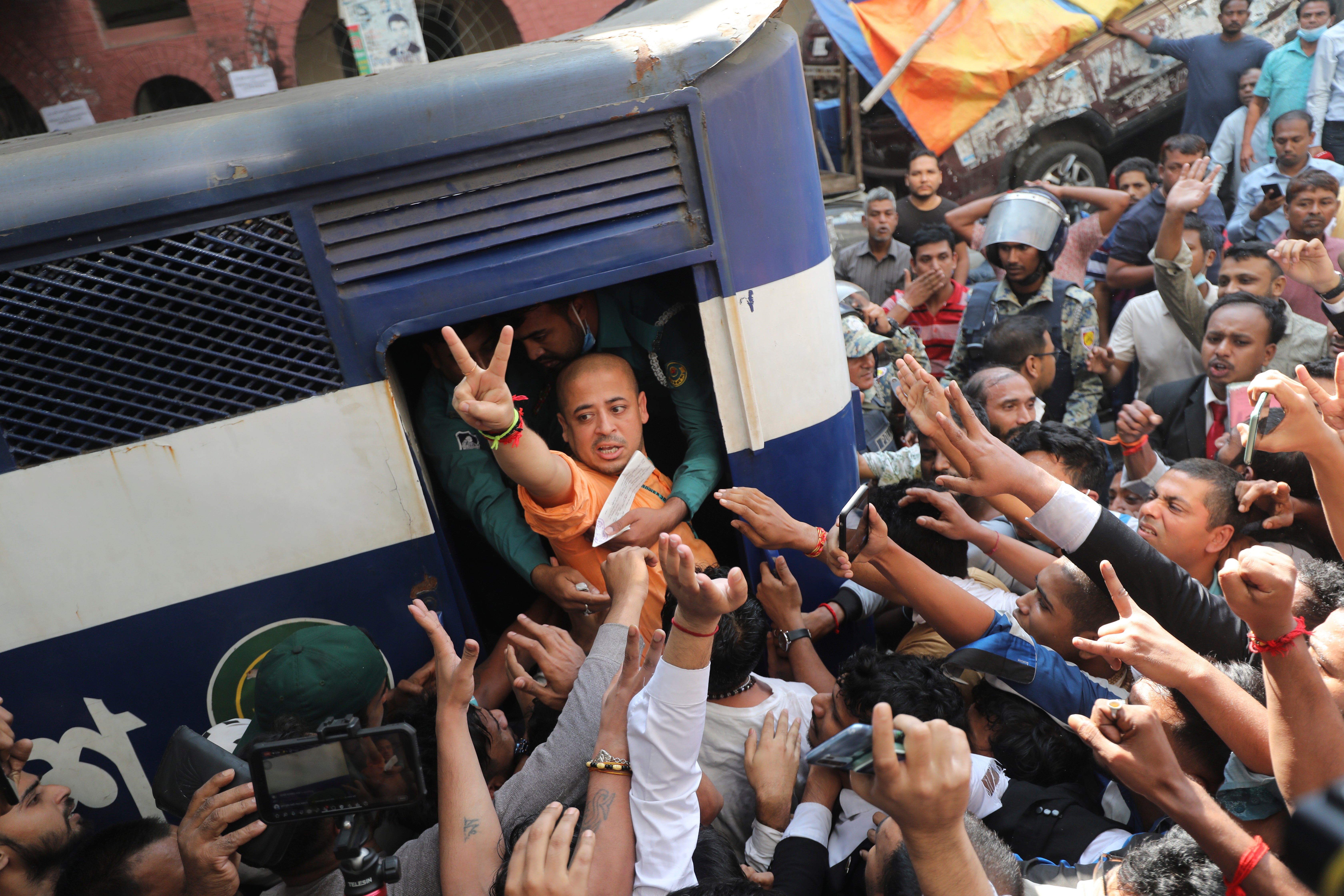 Bangladeshi Hindu leader Krishna Das shows a victory sign as he is taken in a police van after court ordered him detained pending further proceedings in Chattogram