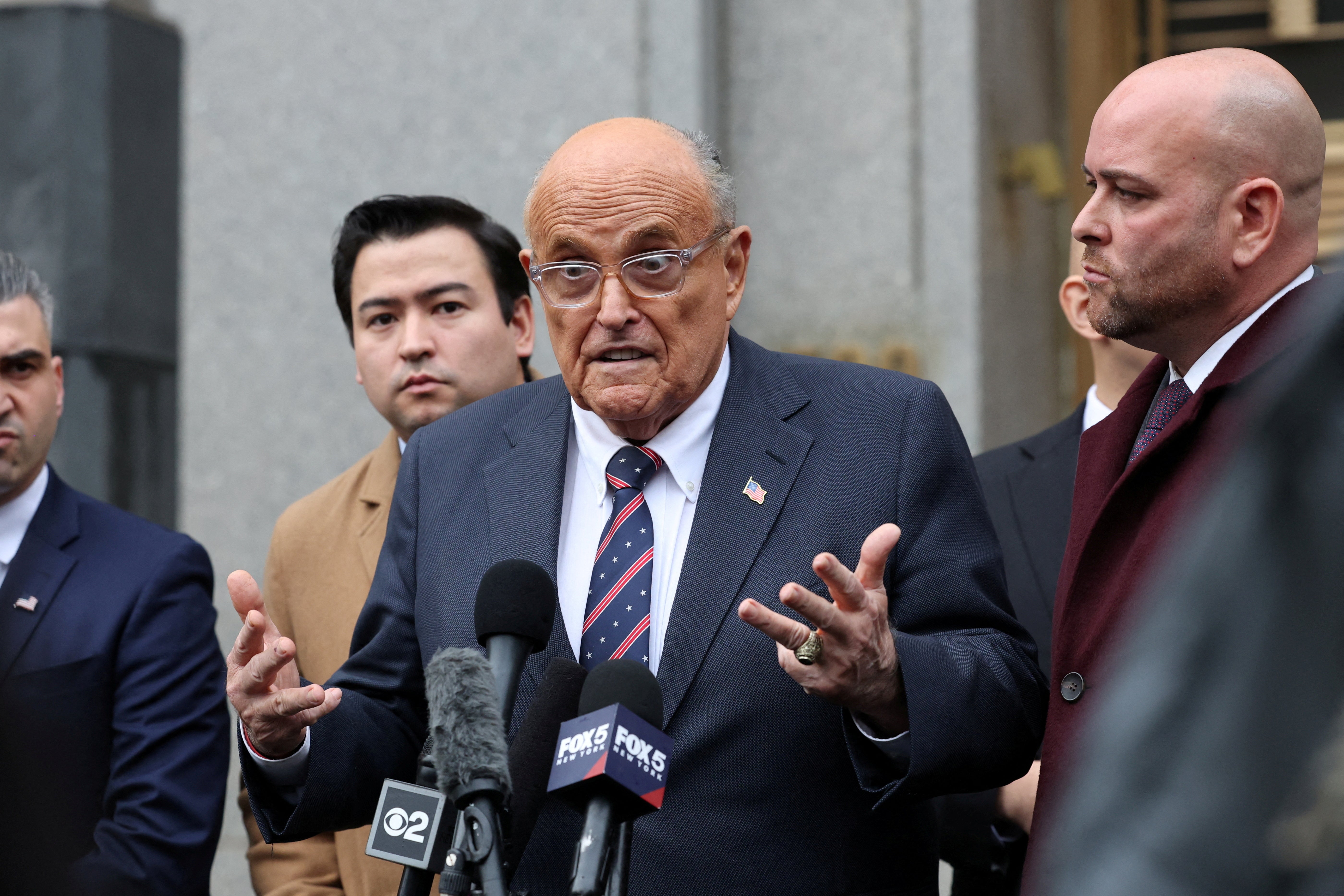 Former Donald Trump lawyer Rudy Giuliani speaks to reporters after leaving a hearing in a case stemming from a blockbuster defamation judgment