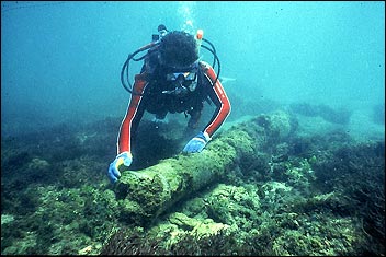 A diver looks on the ocean floor at the site of the Urca de Lima wreck. The ship remains on a natural reef composed of coral, sponges, and marine vegetation, approximately 200 yards from shore