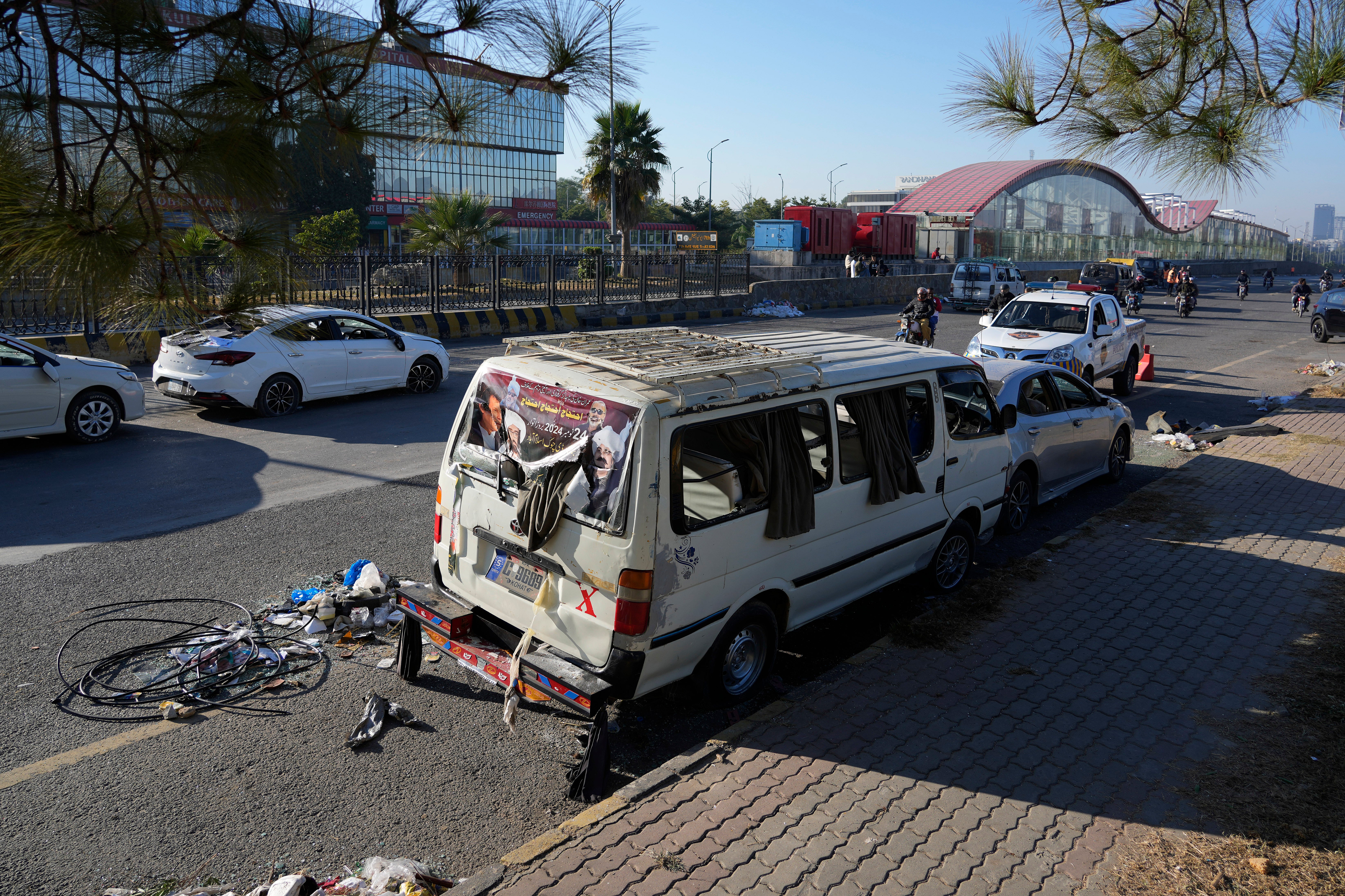 A motorcyclist drives done  the damaged vehicles near  down  by supporters of Khan