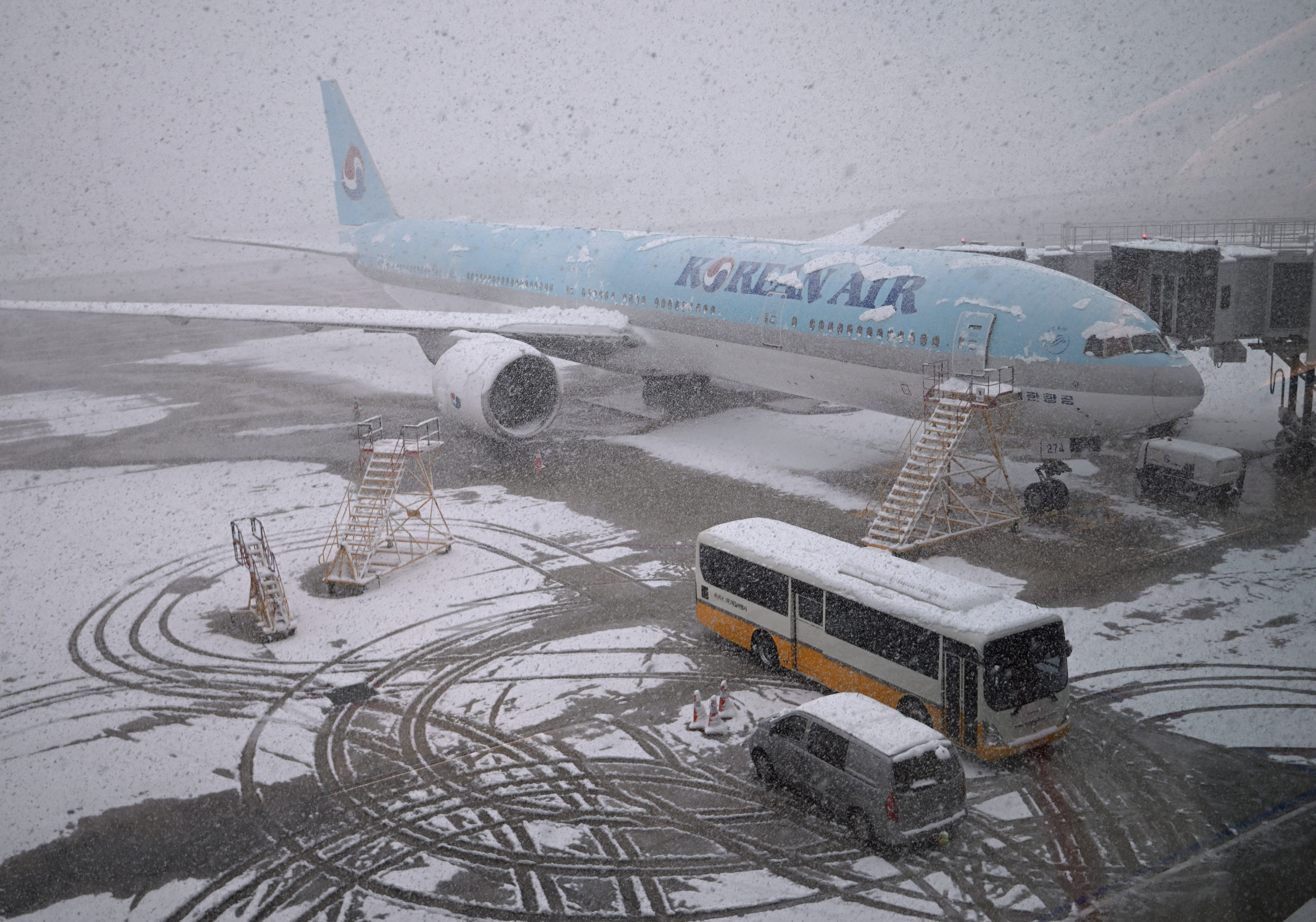 A Korean Air plane is parked on the tarmac during snowfall as seen through a window at Incheon international airpor