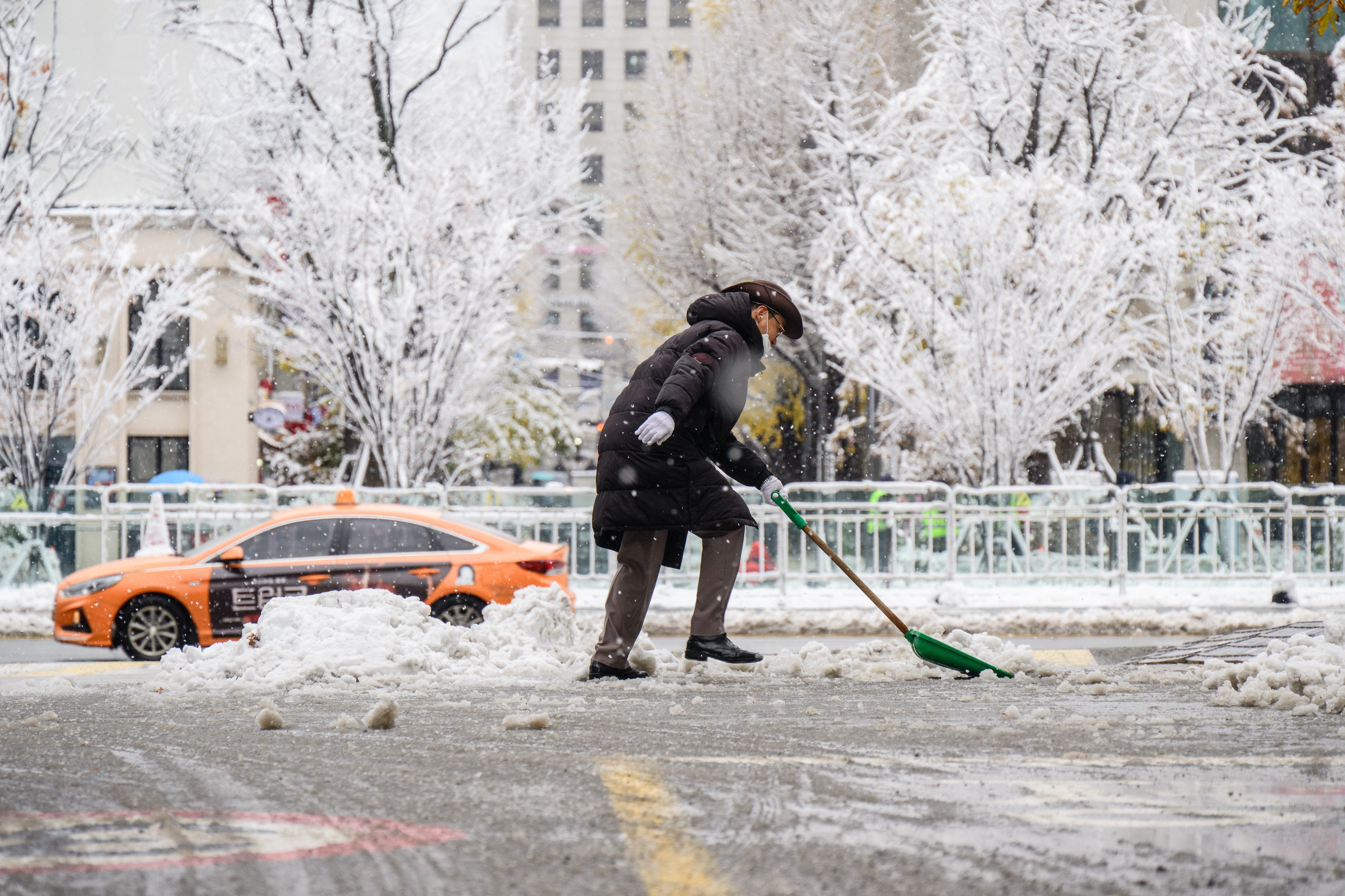 A car park attendant clears a road amid heavy snowfall