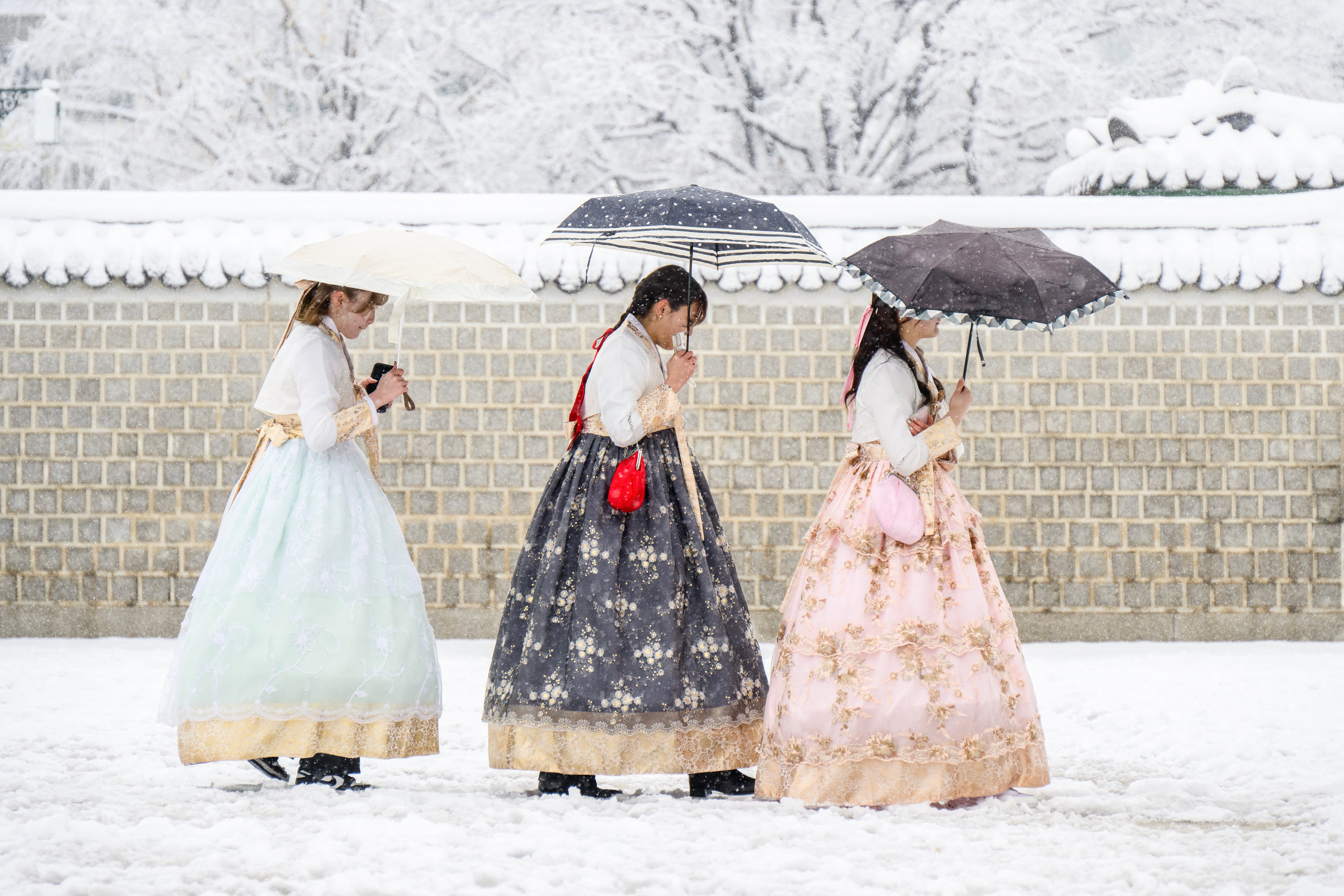 Visitors wearing traditional hanbok dresses are seen on the grounds of Gyeongbokgung Palace amid heavy snowfall