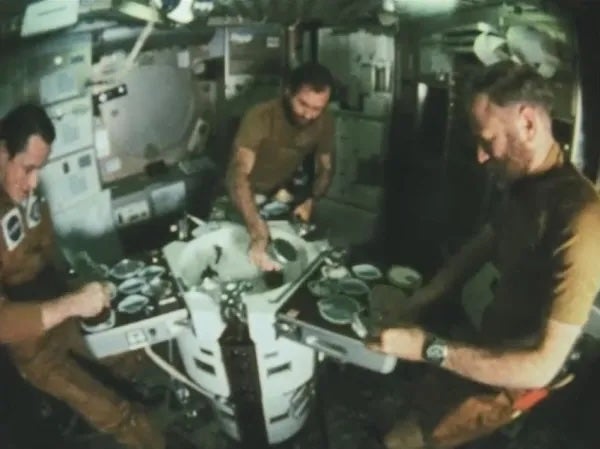 Skylab 4 astronauts Edward Gibson, left, William Pogue, and Gerald Carr, demonstrate eating on Skylab. Skylab, America’s first space station, operated until 1979