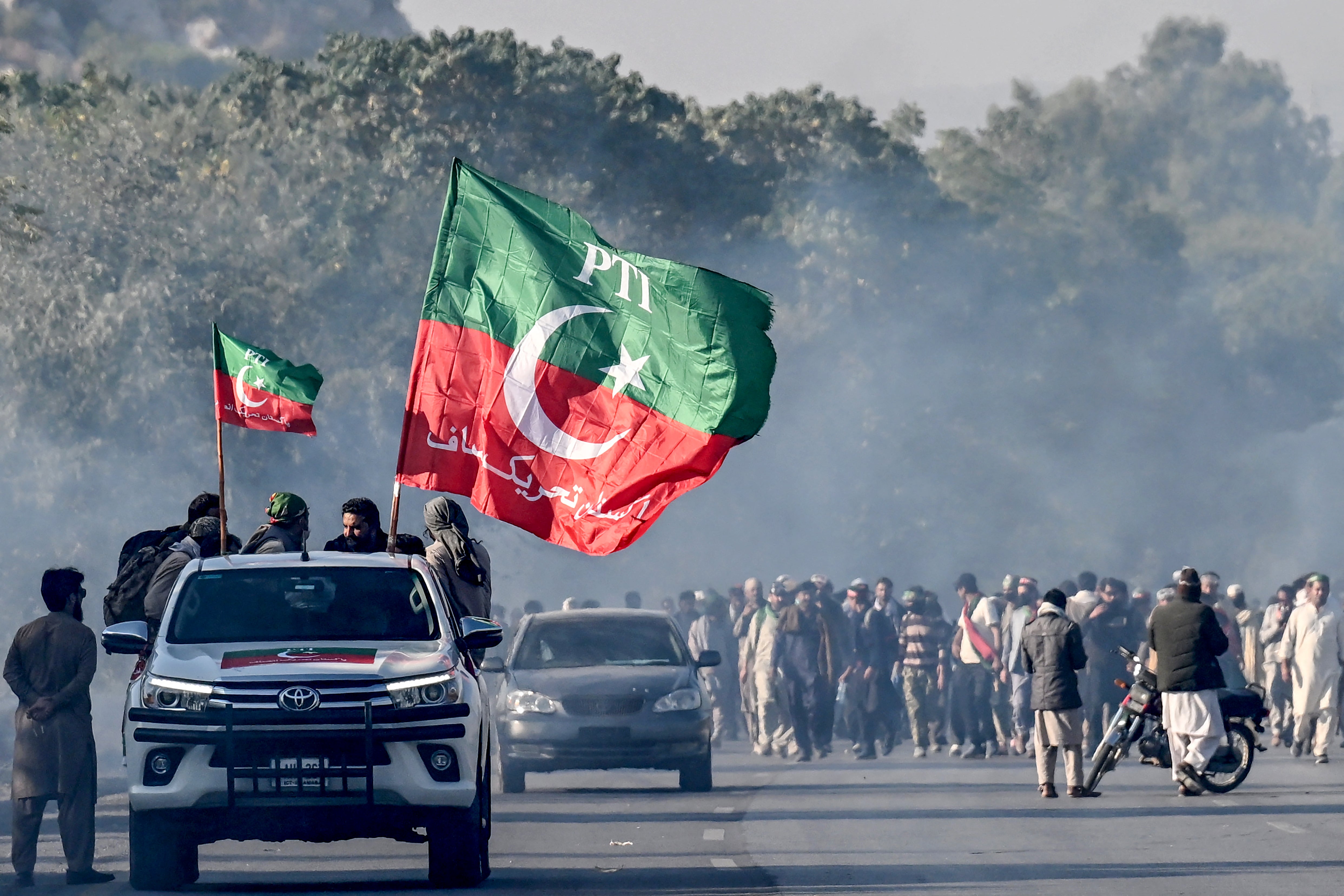 Supporters of jailed former prime minister Imran Khan's Pakistan Tehreek-e-Insaf (PTI) party march towards Islamabad after clearing shipping containers placed by authorities