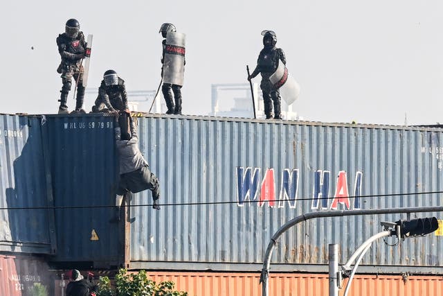 <p>Paramilitary soldiers try to detain supporter of the Pakistan Tehreek-e-Insaf (PTI) party on top of shipping container during protest demanding release of former prime minister Imran Khan at the Red Zone area in Islamabad on 26 November 2024</p>