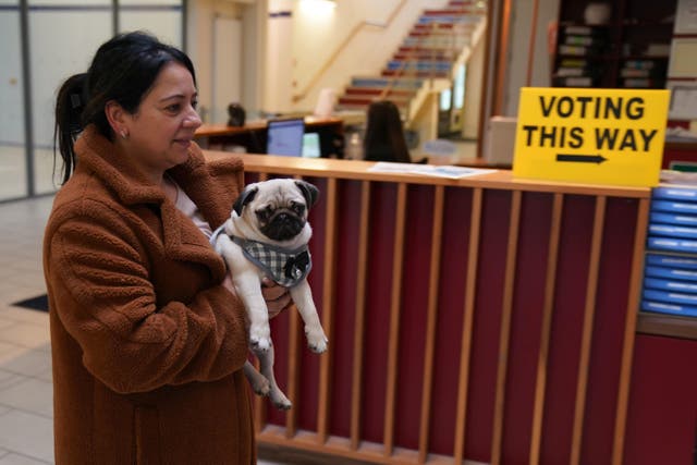 Sonia Higgins, carrying her dog Chico, arrives to cast her vote in Ireland’s General Election (Brian Lawless/PA)