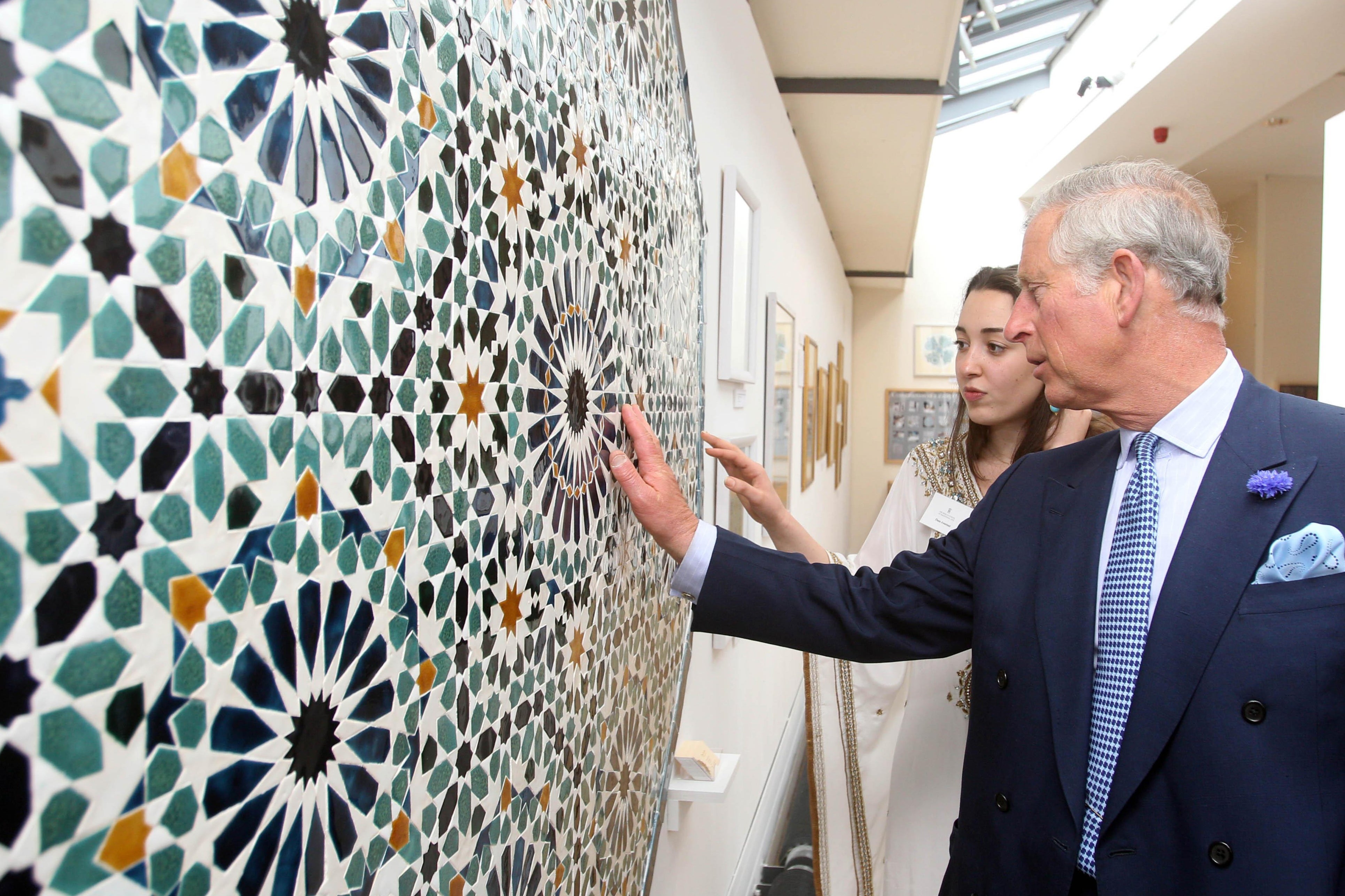 The then Prince of Wales speaks with artist Dana Awartani as he looks at her artwork during a visit to The Prince’s School of Traditional Arts Degree Show in London