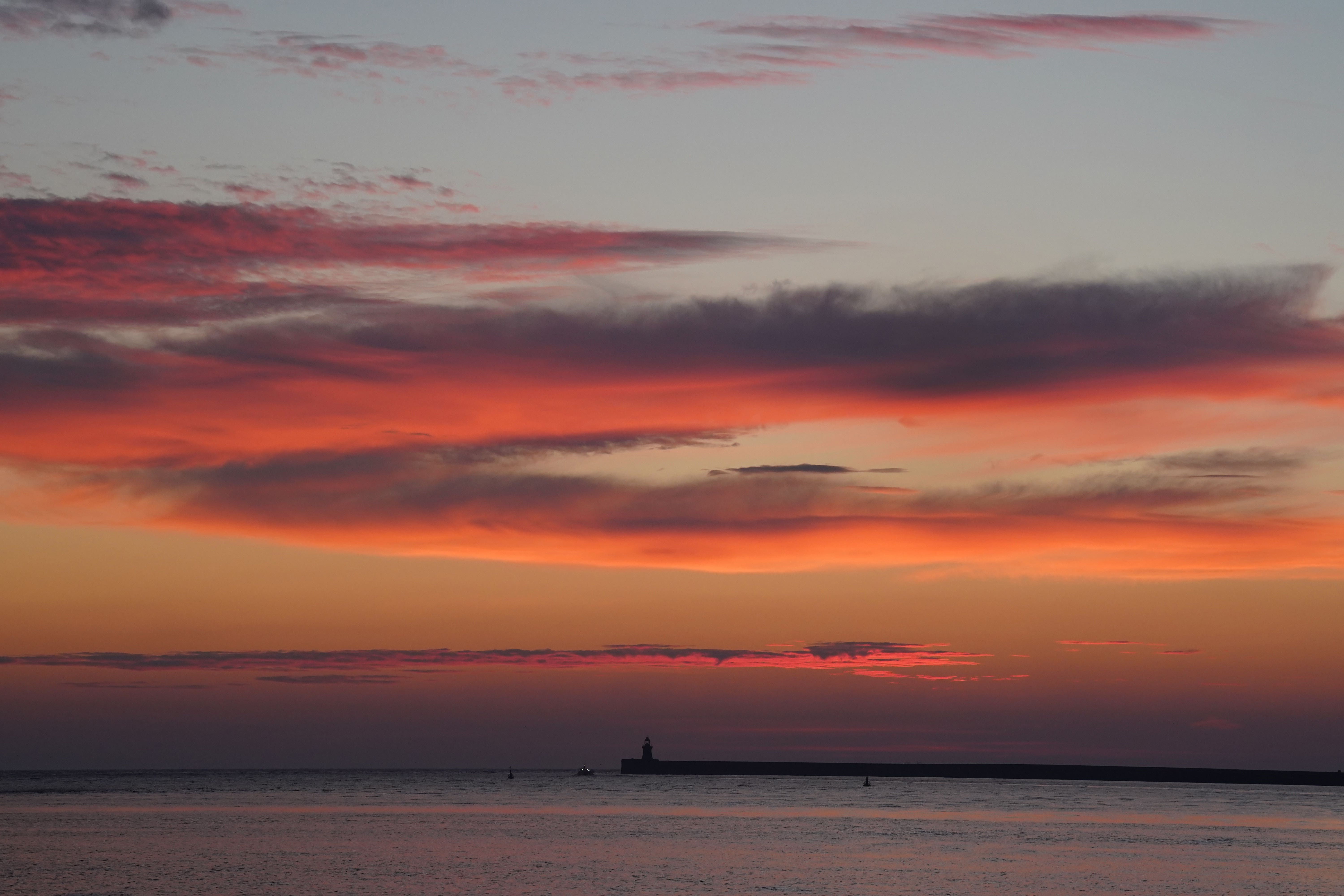 The sun begins to rise behind South Shields lighthouse on the North East coast (Owen Humphreys/PA)