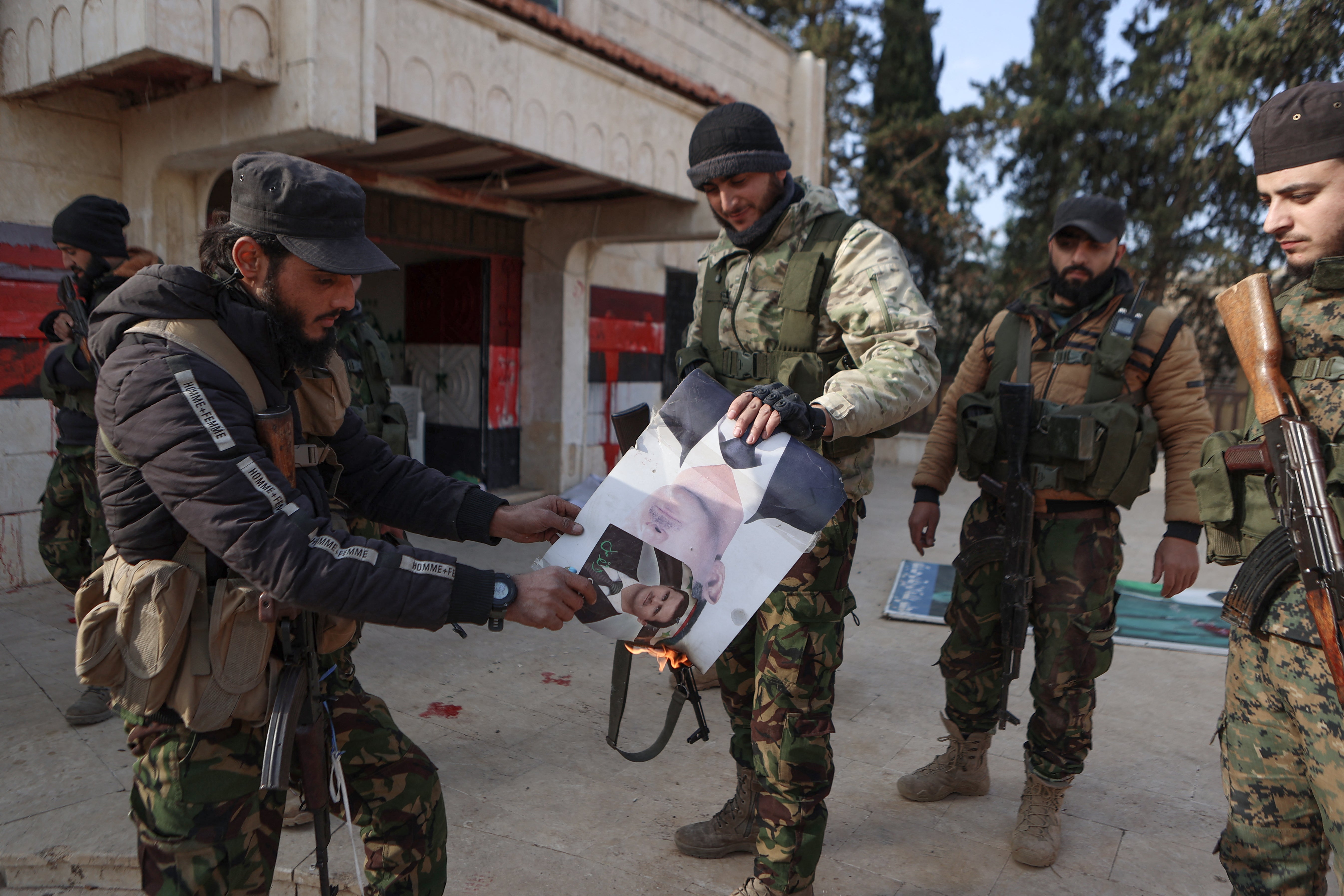 Fighters burn a picture of Assad in front of a building that was seized by jihadists in Zarbah, near Aleppo