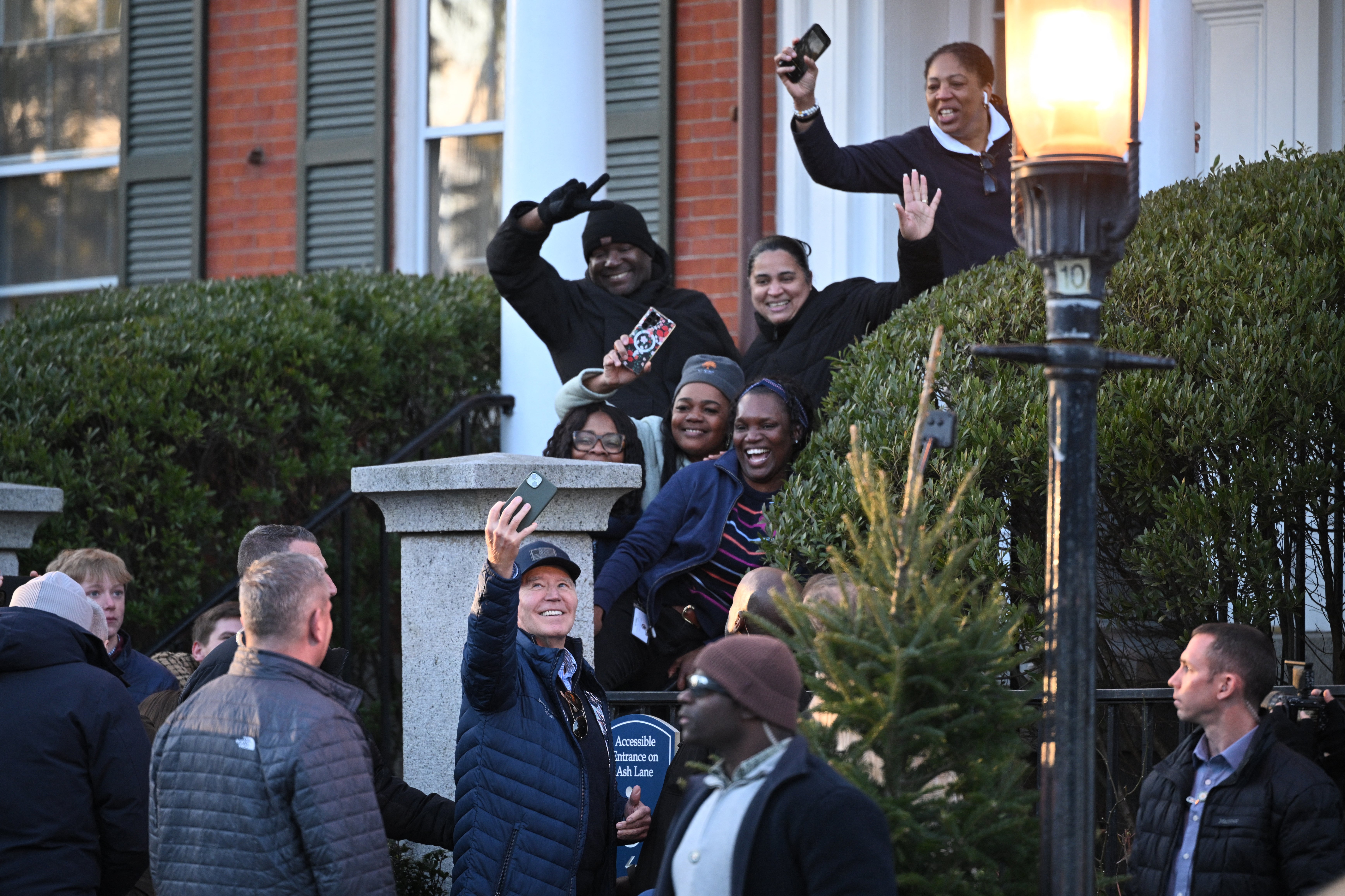 President Joe Biden (bottom, C) poses for a selfie in front of a hotel with hotel staff in Nantucket, Massachusetts