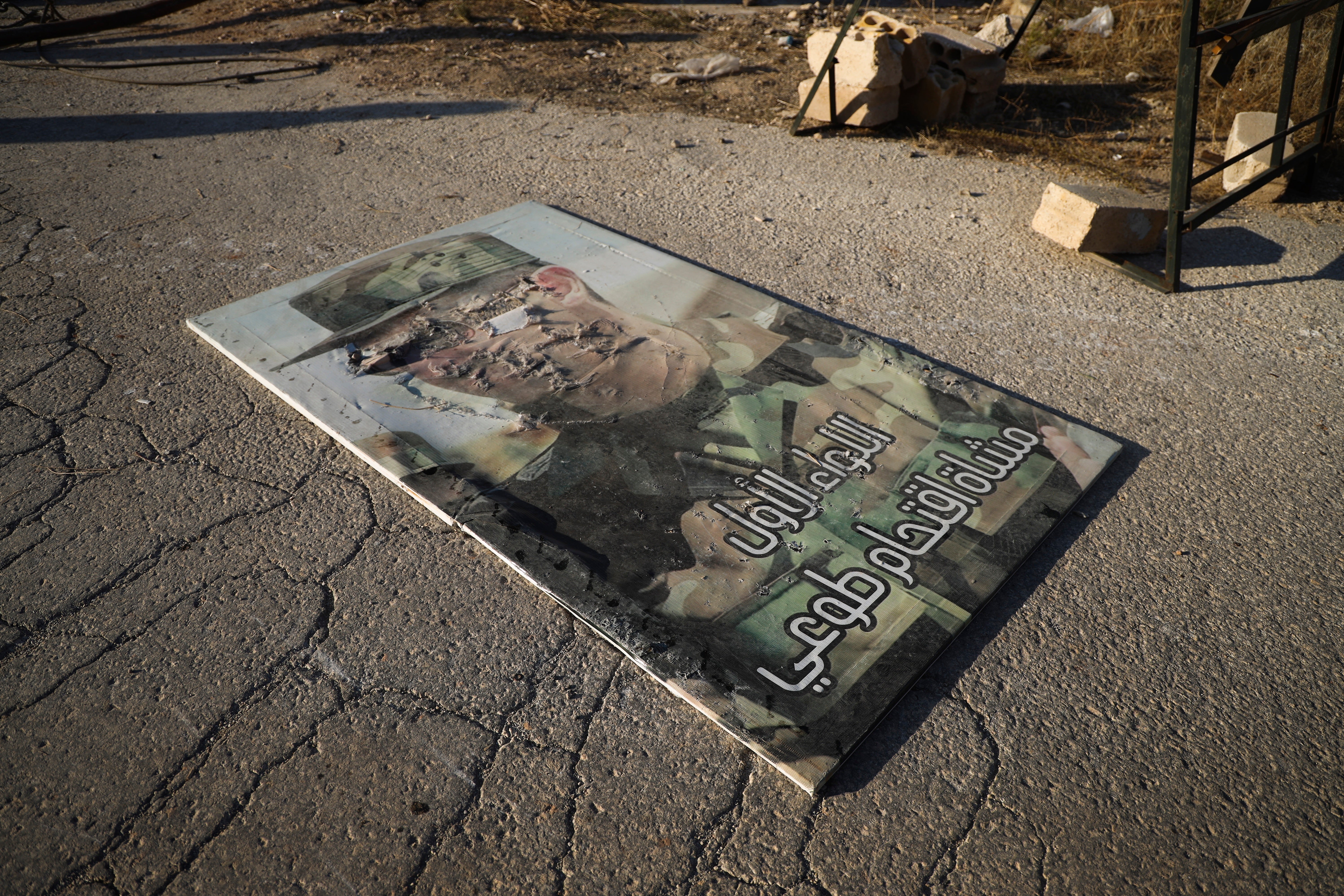 A defaced portrait of Syrian president Bashar al-Assad lies on the ground in the town of Maarat al-Numan, southwest of Aleppo