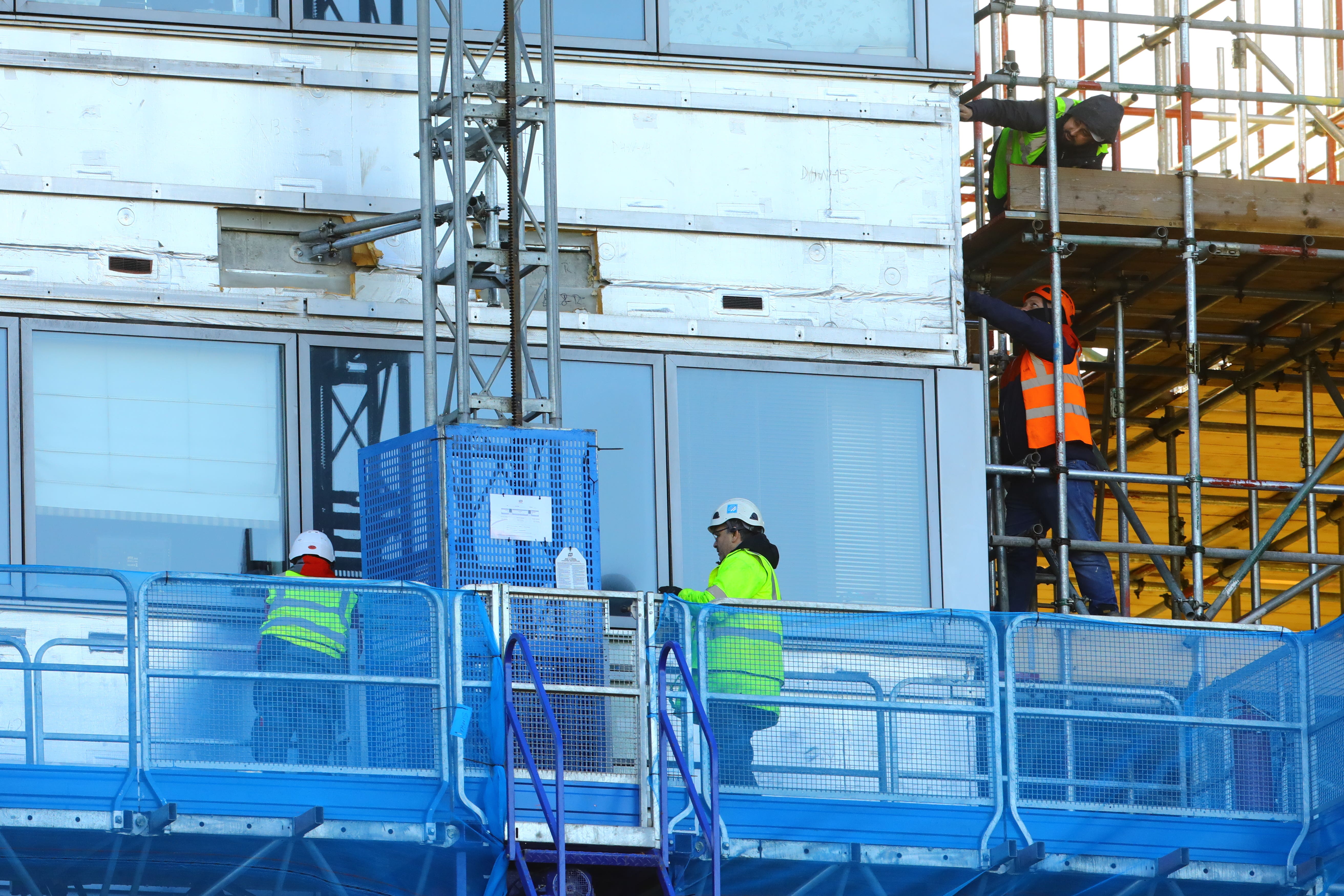 Workers remove the cladding from the facade of a block of flats (Aaron Chown/PA)