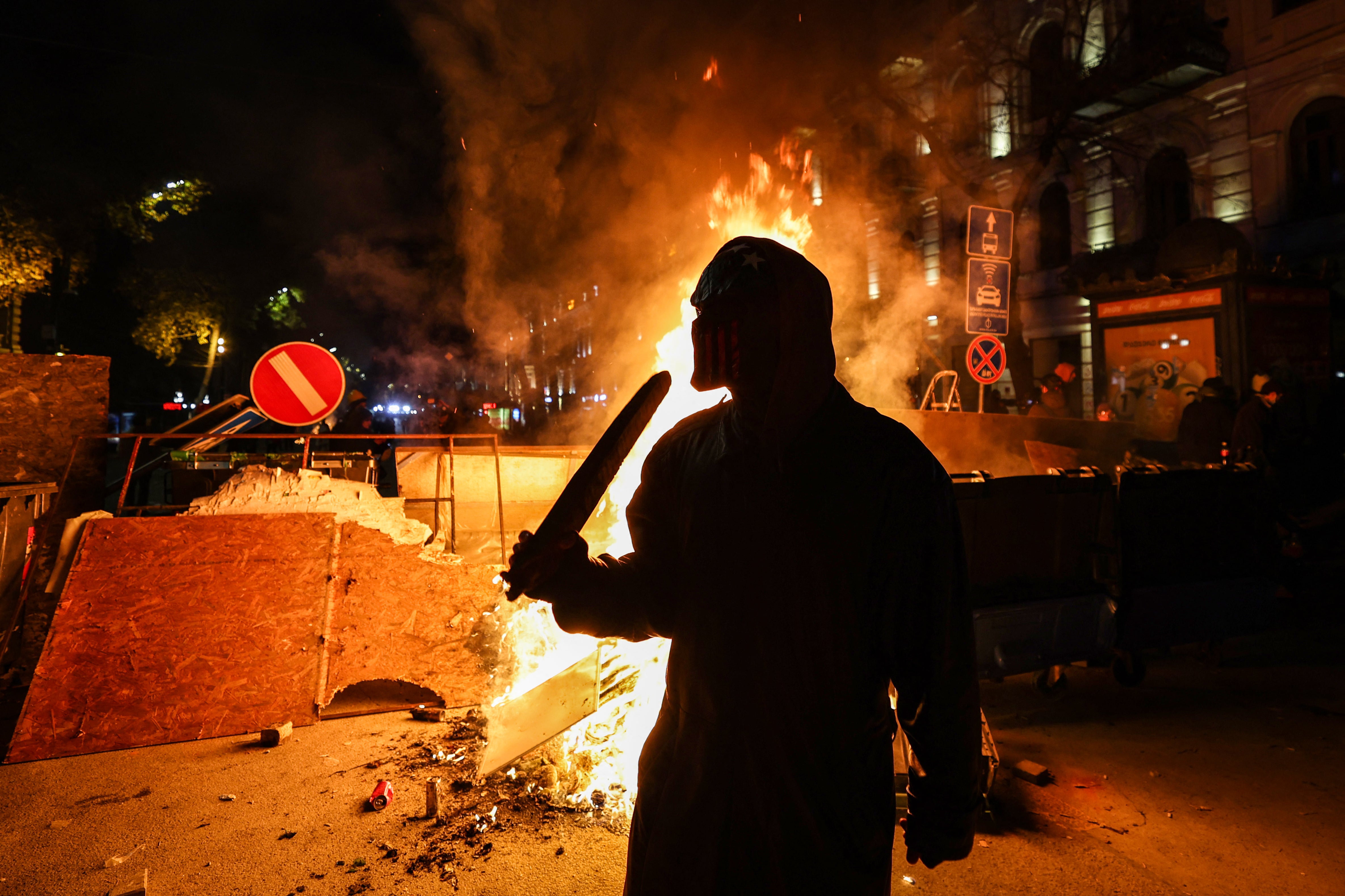 Protesters light a fire at the base of a makeshift barricade erected in a street in Tbilisi