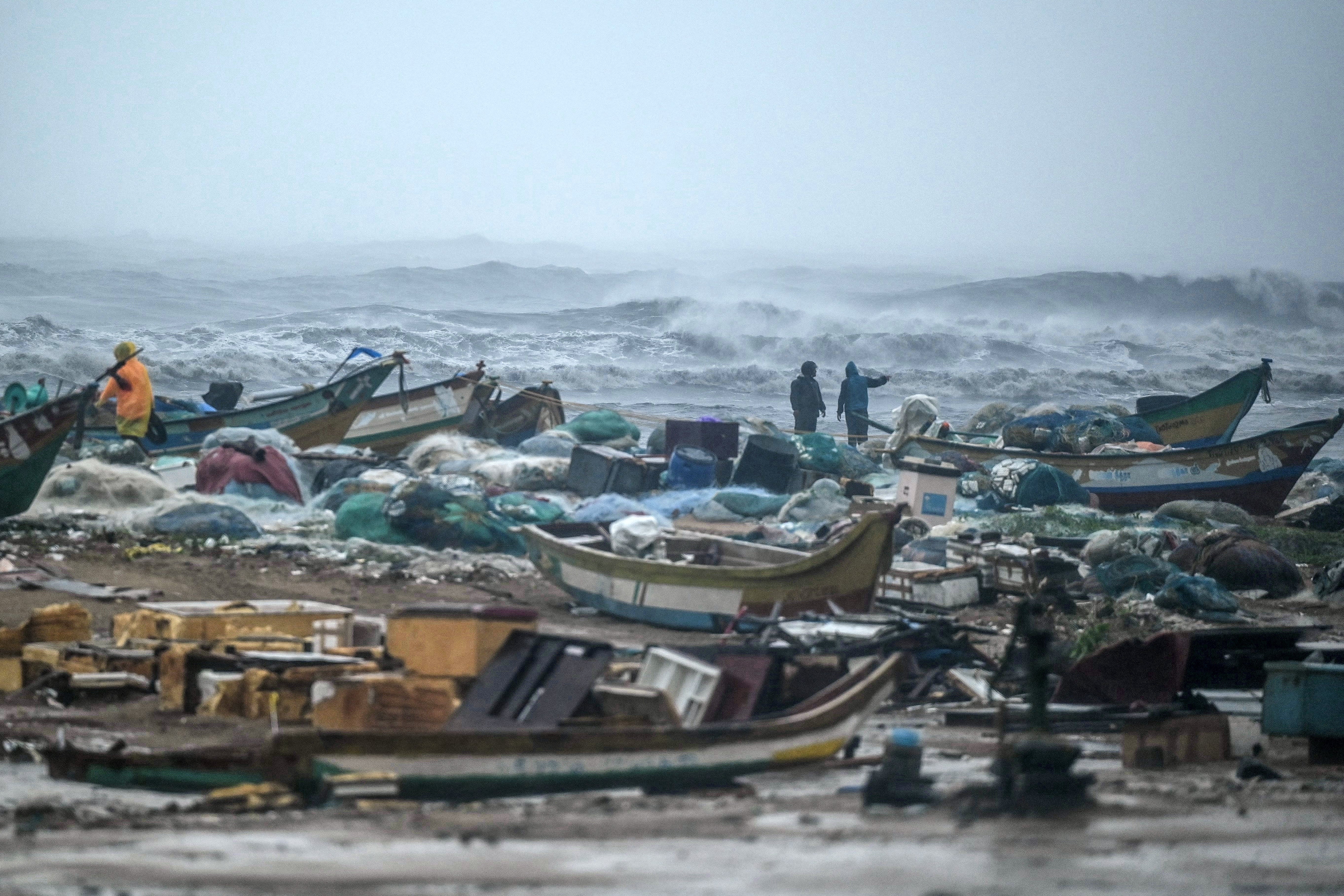 Fishermen pull their boats at Marina Beach amid heavy winds and rainfall in Chennai on 30 November 2024