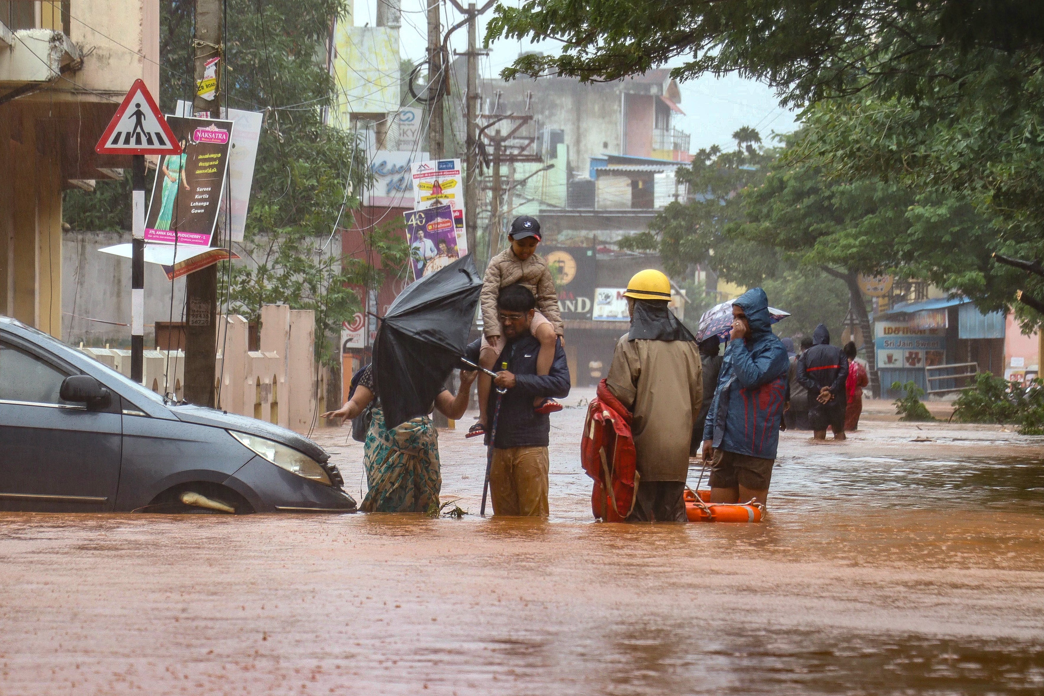 People stand in a flooded street after heavy rainfall in Puducherry on 1 December 2024