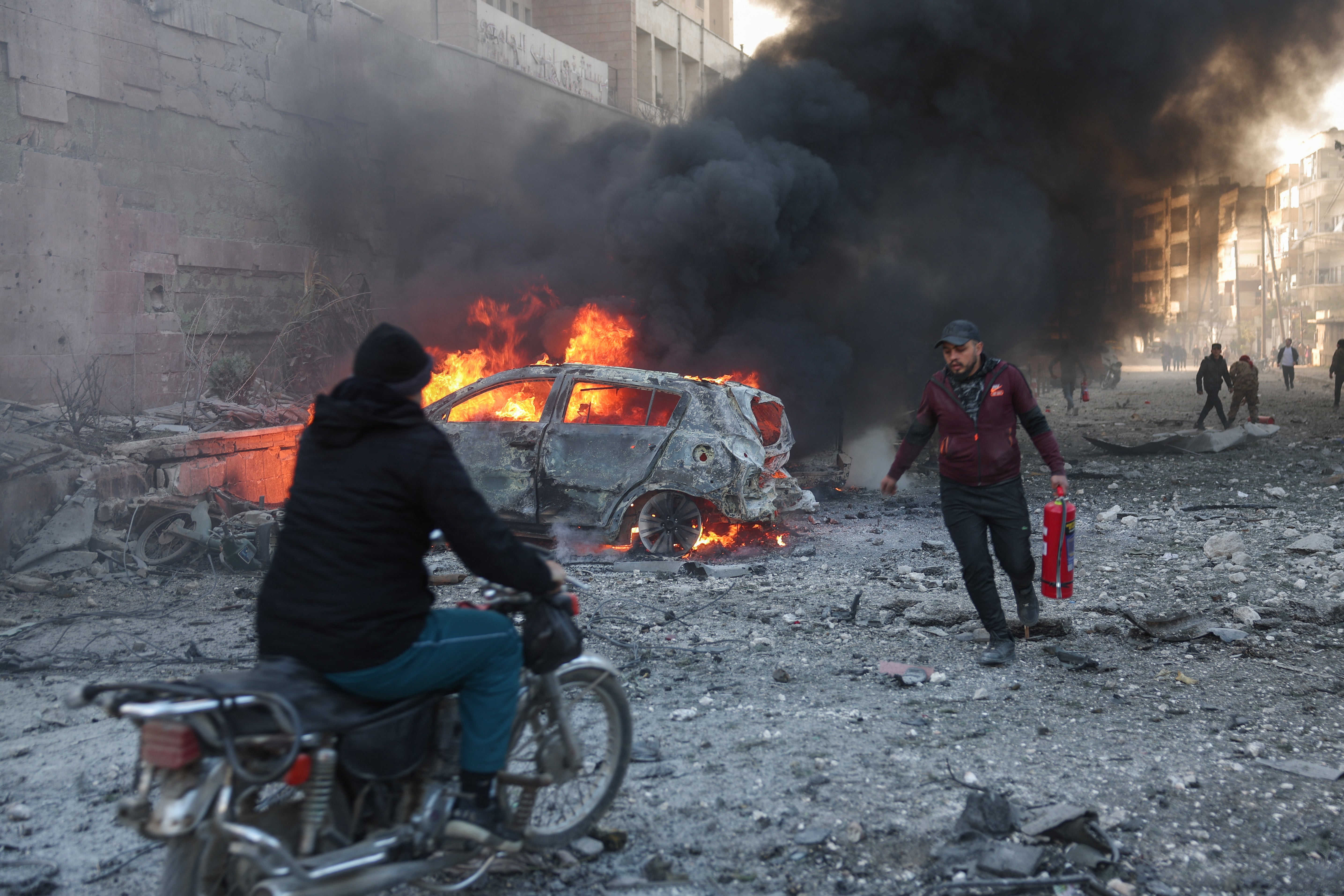 People try to extinguish fires following an airstrike that targeted Syria's rebel-held northern city of Idlib