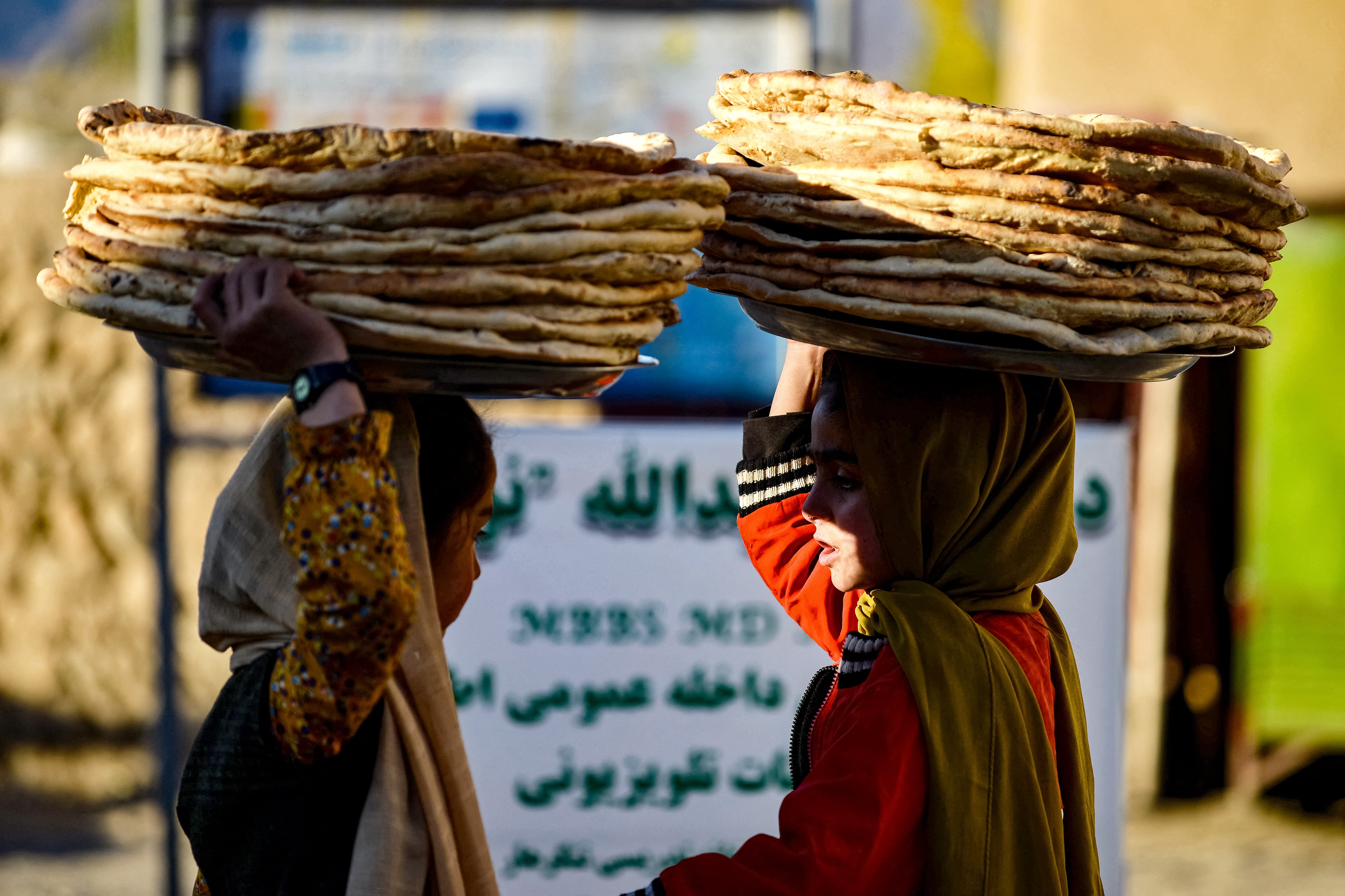 Afghan girls selling bread look for customers at a market in Fayzabad district of Badakhshan province on 26 November 2024