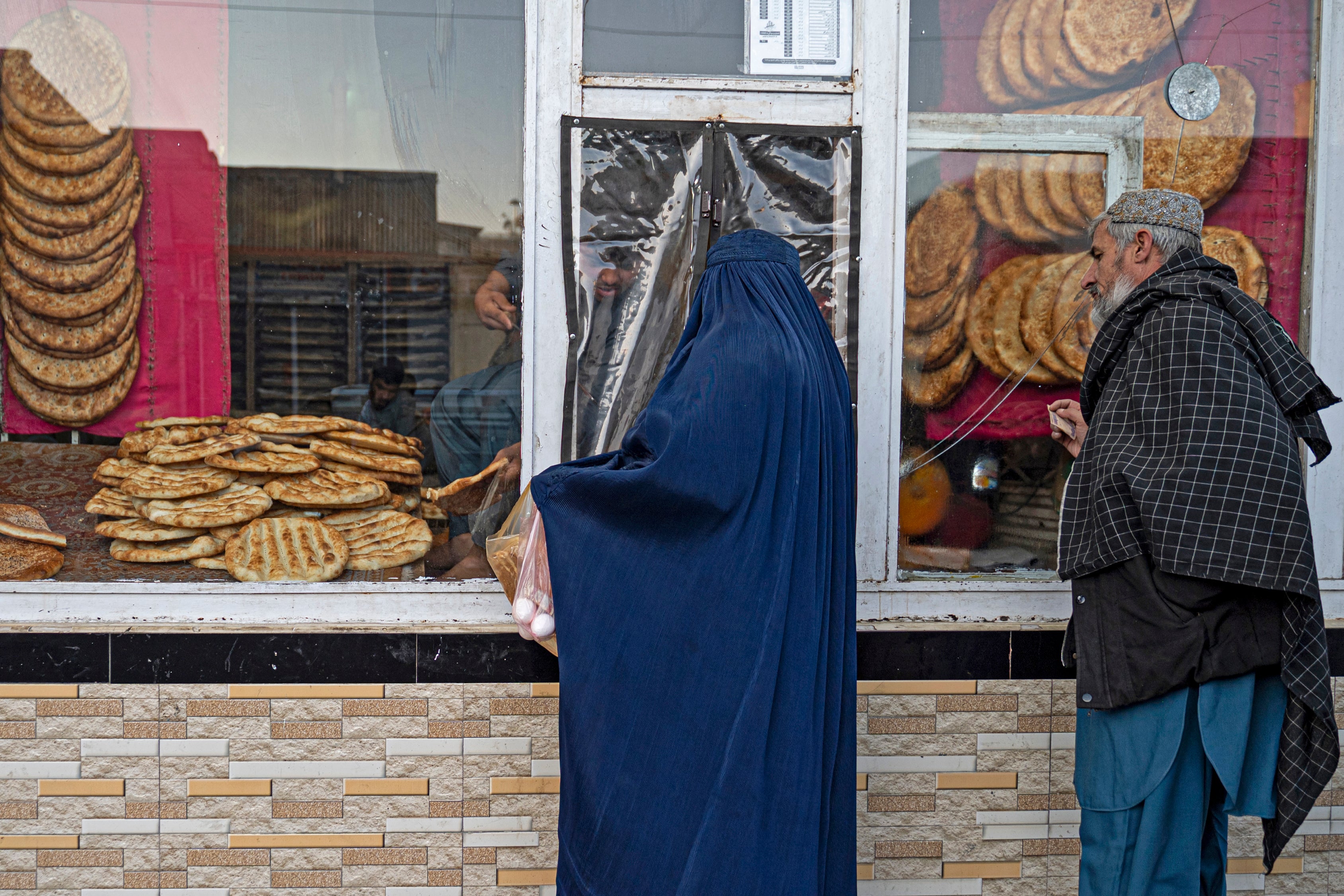 Afghans buy bread from a roadside bakery in Kabul