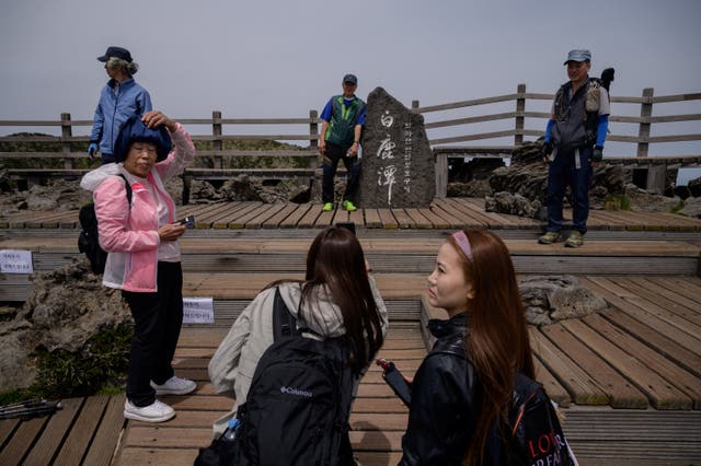 <p>File: Hikers take photos at a viewing deck at the summit of the Hallasan volcano, or Mount Halla, on Jeju island</p>