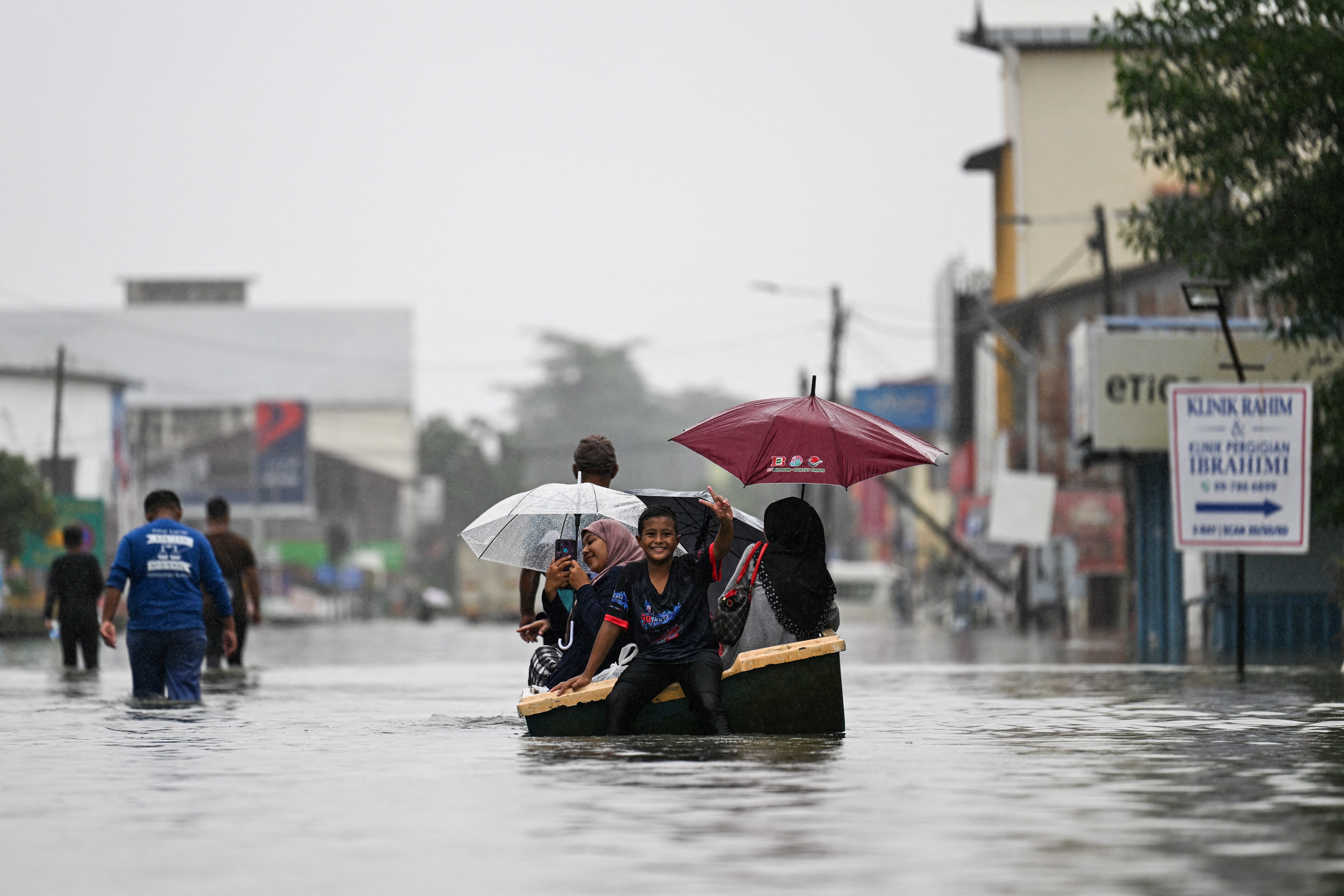 2024 年 11 月 30 日，马来西亚巴西富地，暴雨期间，人们乘船穿过被洪水淹没的街道