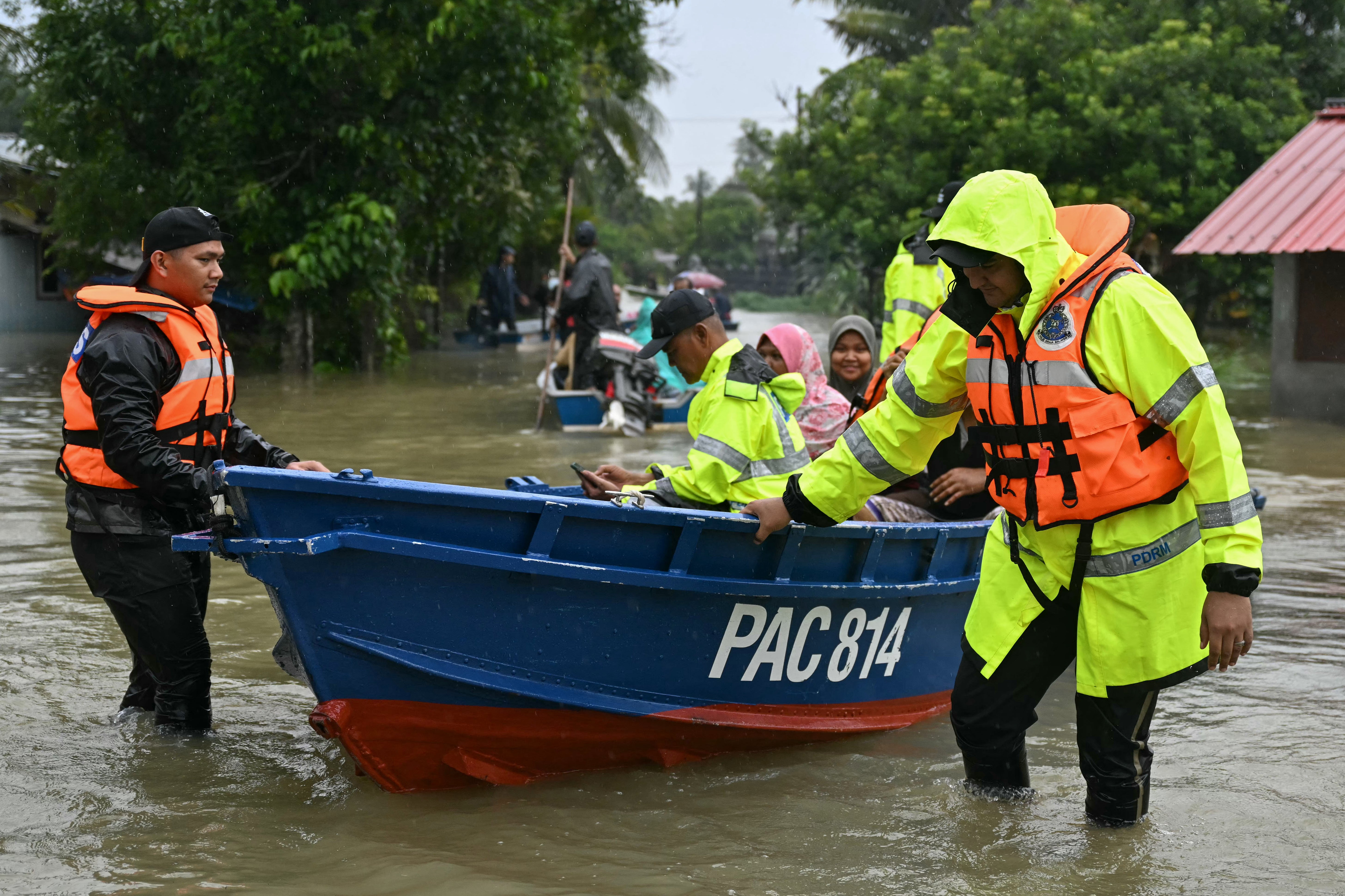 道北连日暴雨后，马来西亚皇家警察乘船运送居民穿过洪水