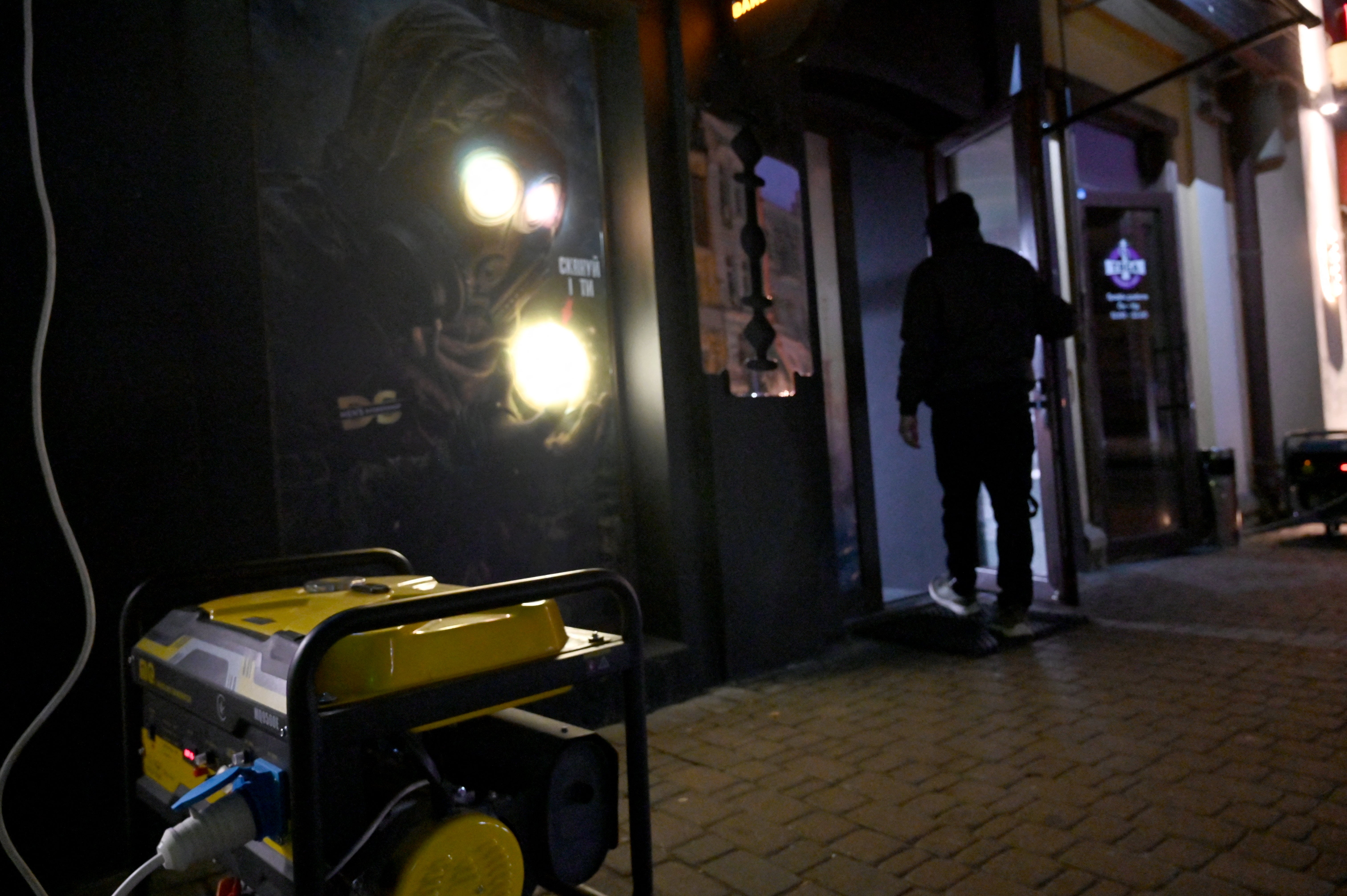 A visitor walks past a power generator outside as he enters in a cafe during a partial blackout in Kyiv