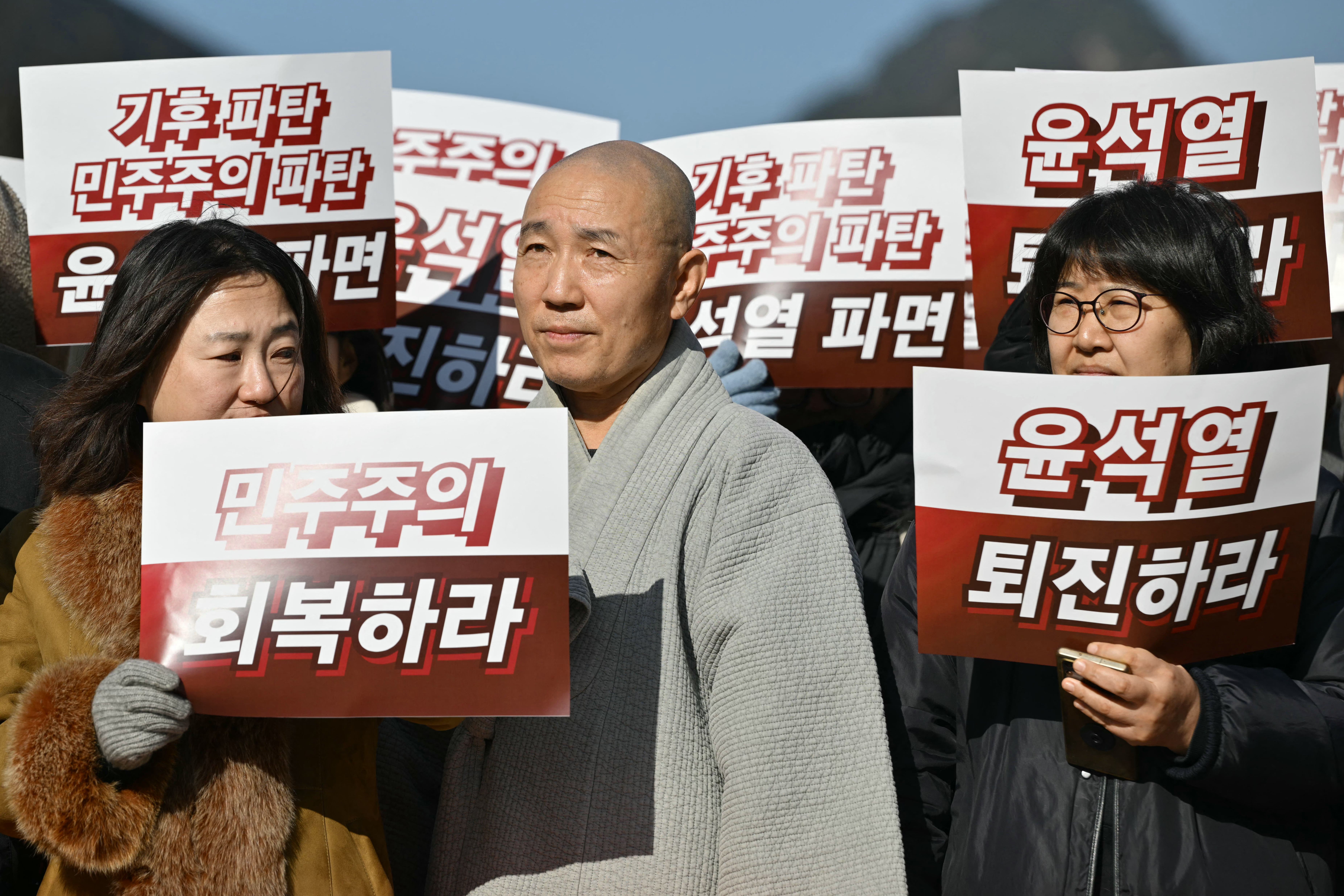 Protesters hold placards that read “Restore democracy (front L)” and “Resign Yoon” during a rally calling for the resignation of South Korea President Yoon Suk Yeol at Gwanghwamun Square in Seoul on December 4, 2024, after martial law was lifted. Yoon faced demands to resign on December 4 after his short-lived attempt to impose martial law was voted down by lawmakers and brought thousands of protesters to the streets