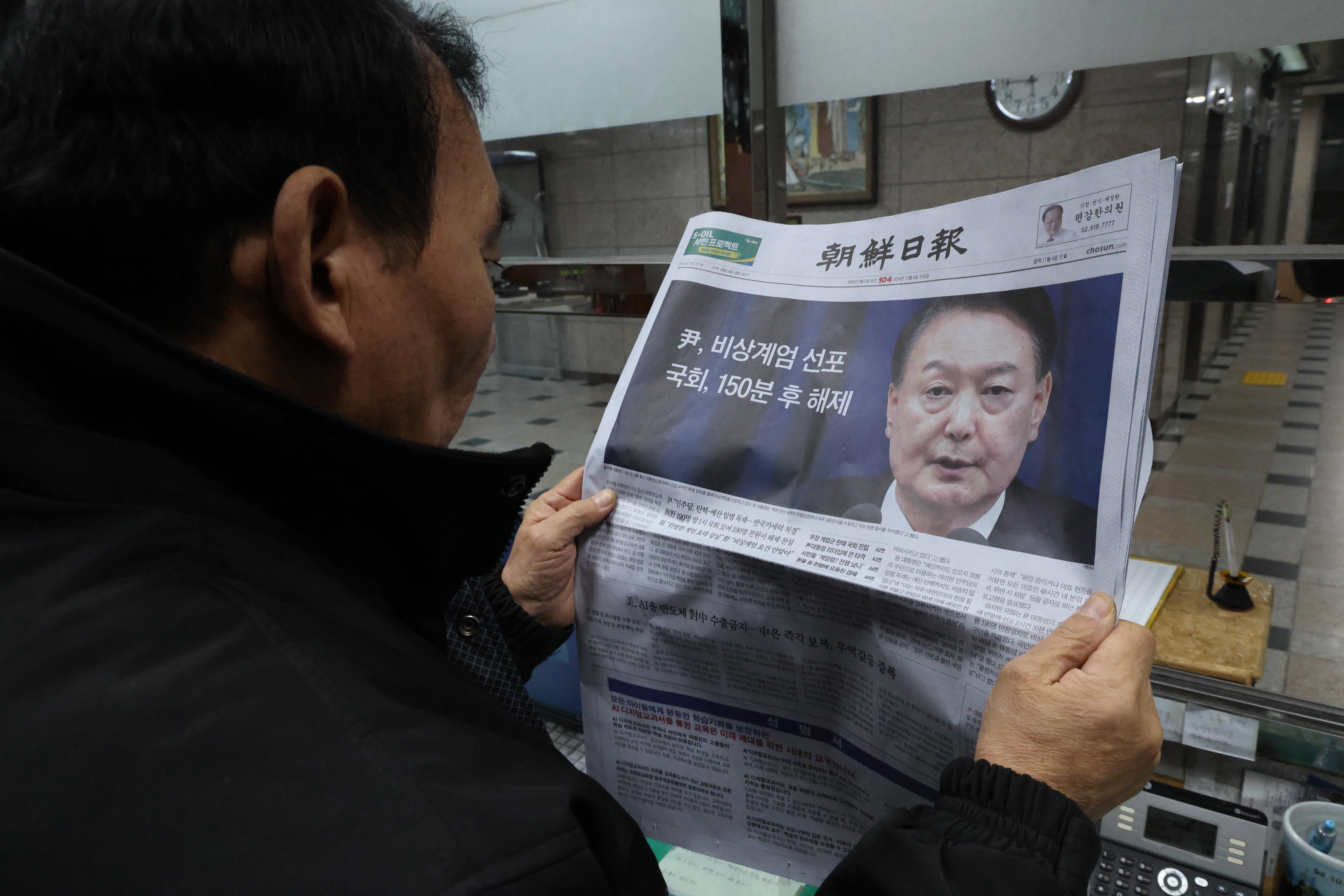 A man looks at a newspaper reporting South Korean President Yoon Suk Yeol announced his intention to lift the emergency martial law in Seoul