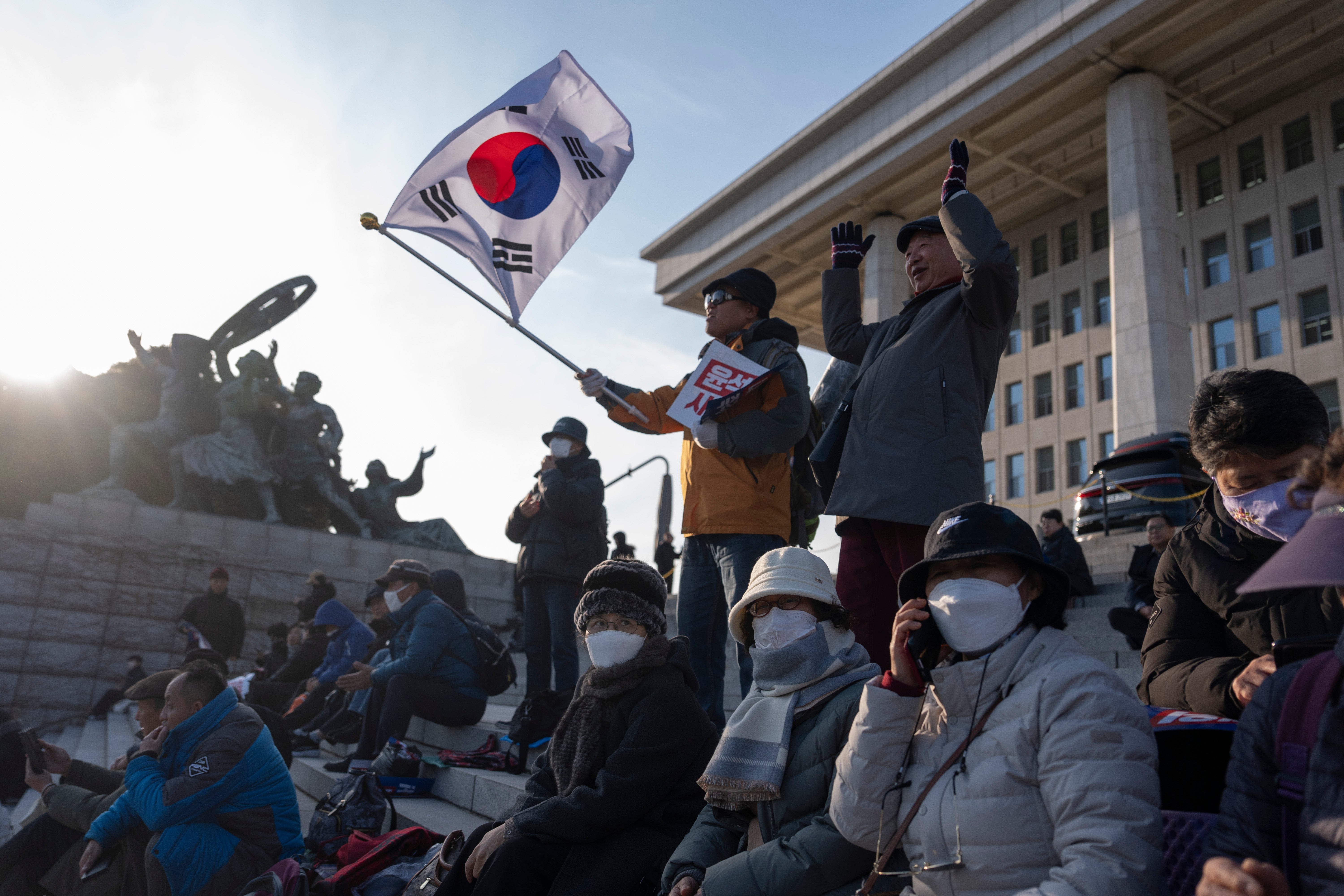 A protester waves a South Korean flag as he joins others gathering outside the National Assembly in Seoul