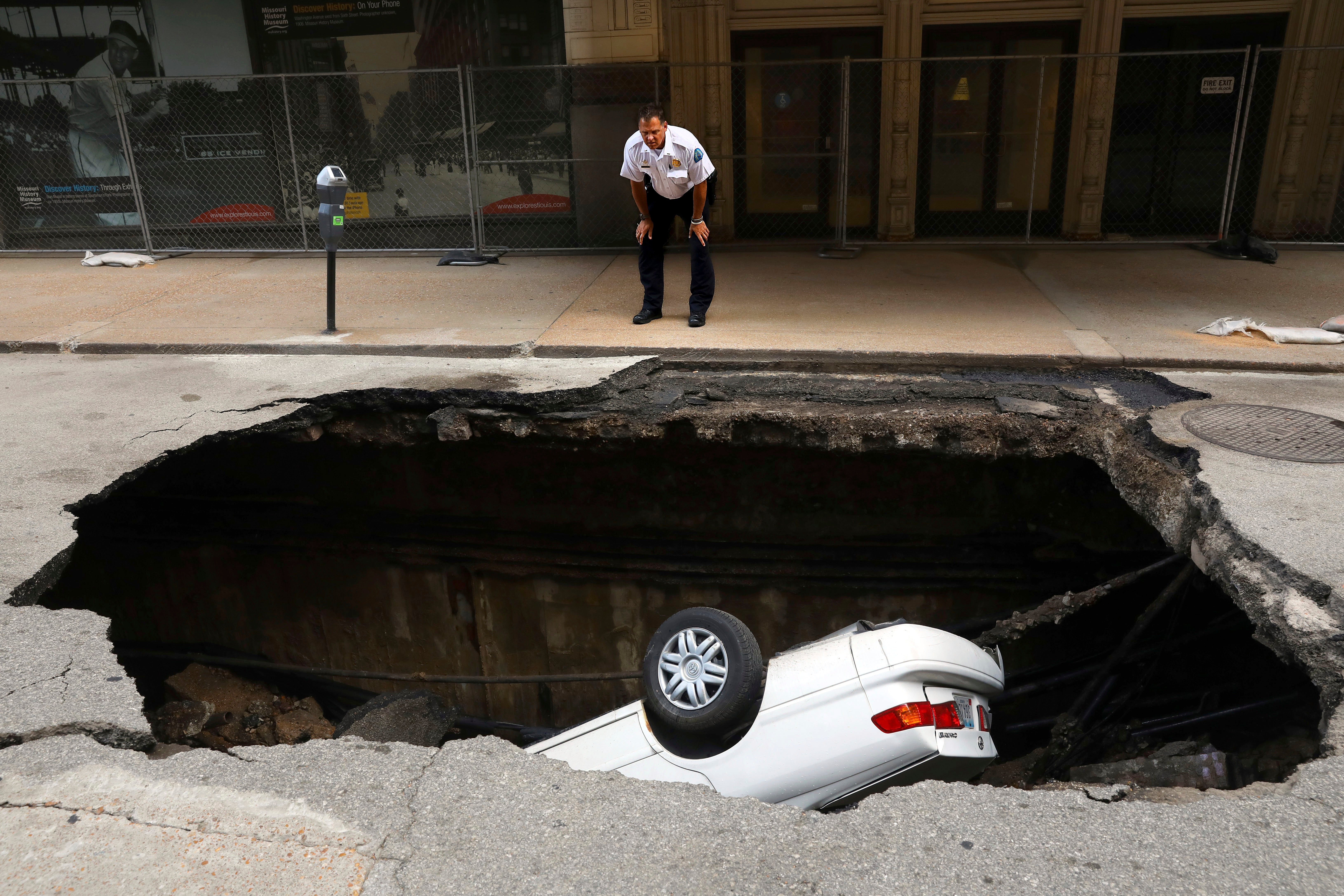 A St. Louis police officer looks over a large hole in 6th Street, Thursday, June 29, 2017