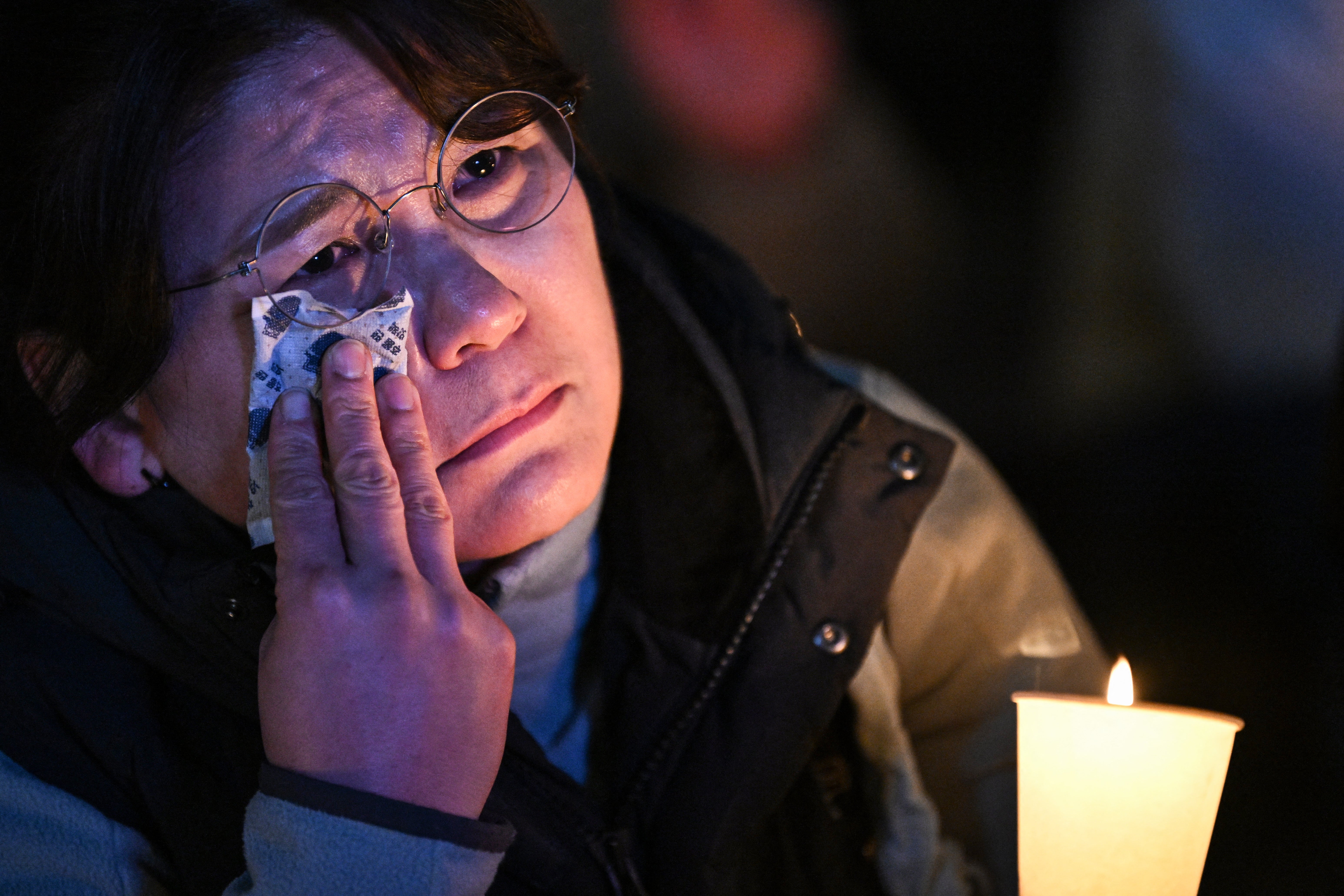 A woman reacts as she takes part in the candlelight vigil