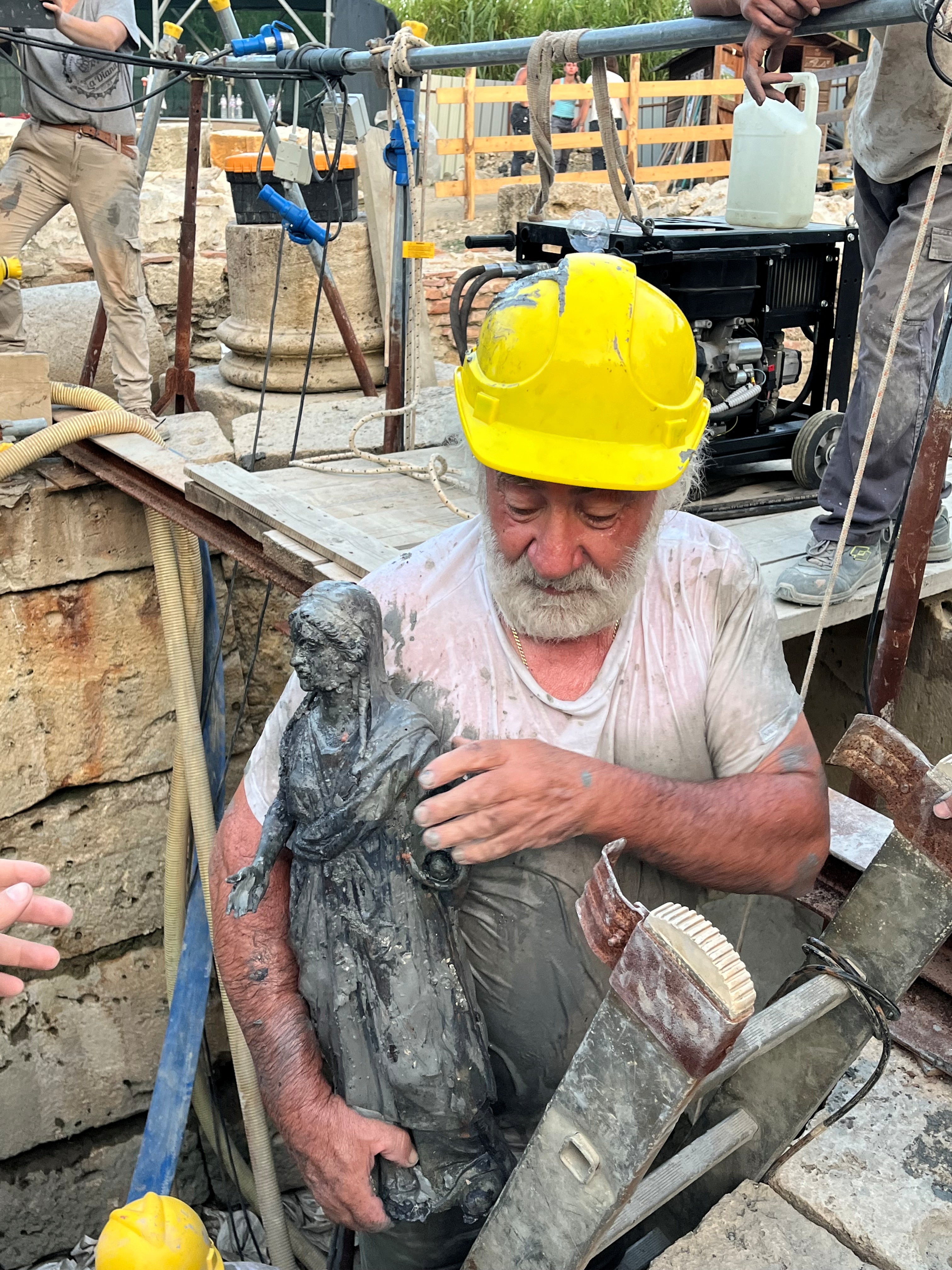 The so-called praying woman statuette is shown by a worker after it was discovered and pulled out from the muddy ruins of an ancient spa in San Casciano dei Bagni, a hilltop village in southern Tuscany still home to popular thermal baths, in Grosseto, Italy