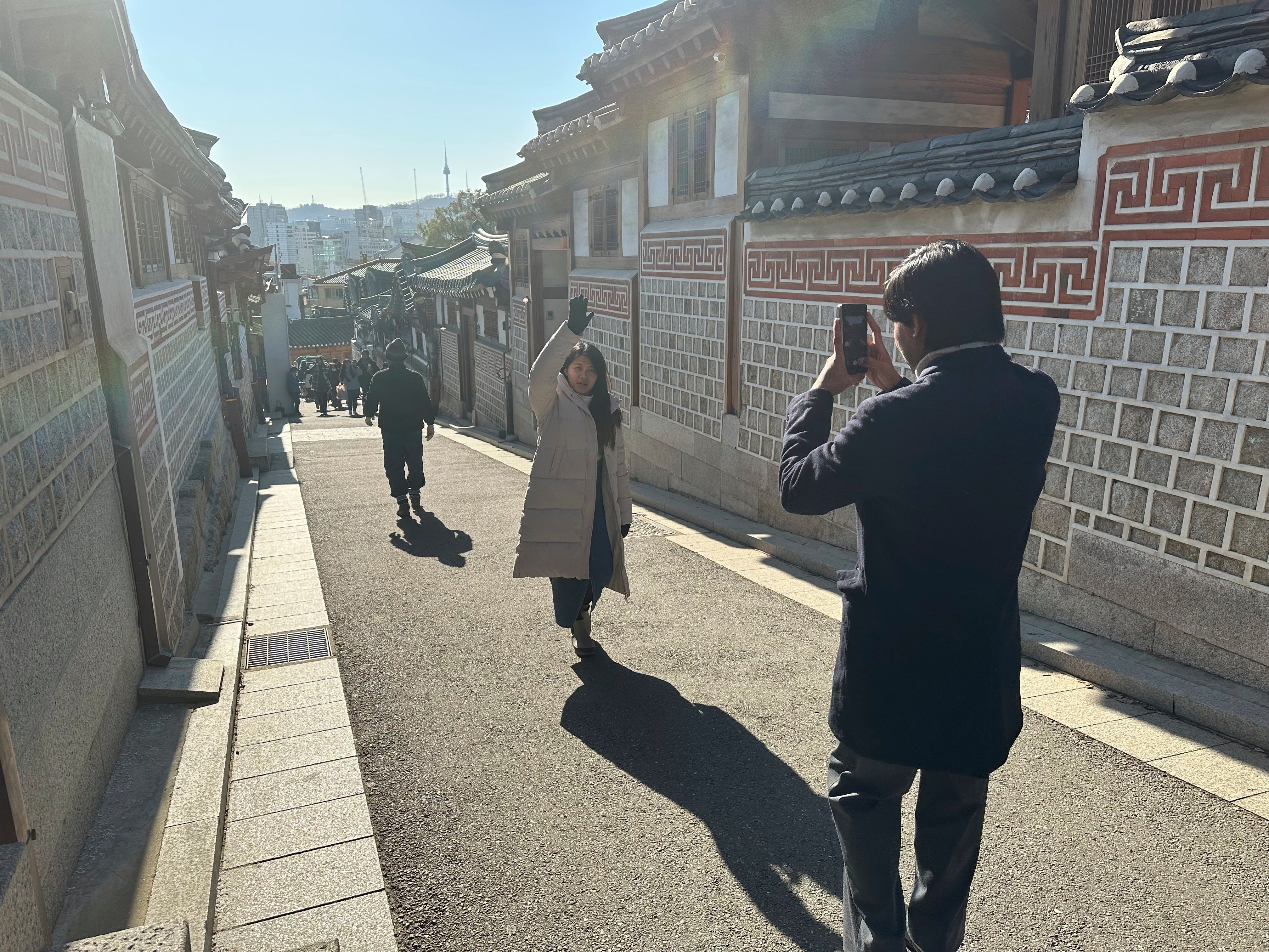 Tourists wander taking photos of the residential neighborhood and its many restored traditional houses in the Bukchon Hanok Village in Seoul on Wednesday