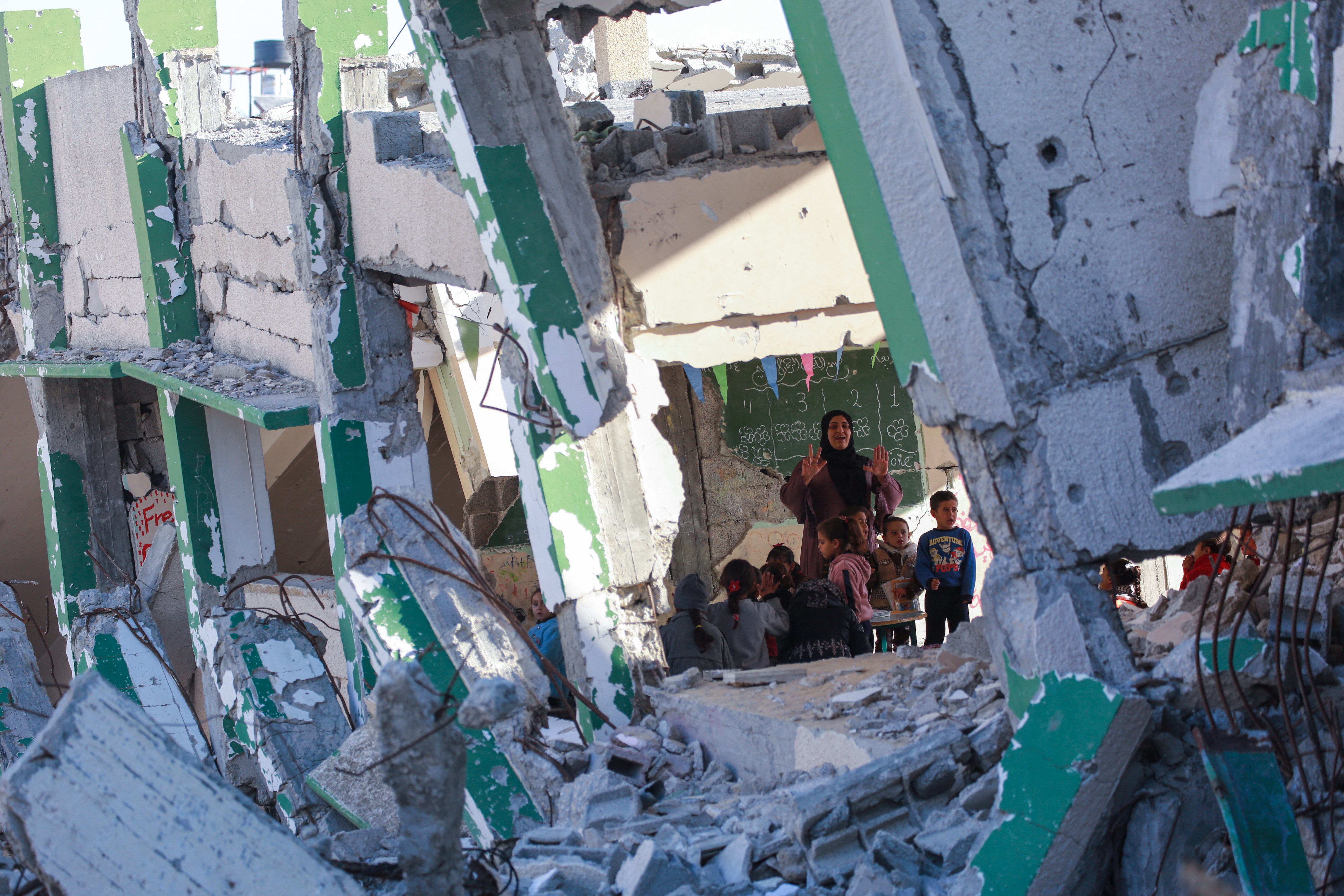 <p>Palestinian teacher Doha al-Attar runs a class for children in a heavily damaged classroom in Khan Younis, Gaza Strip</p>
