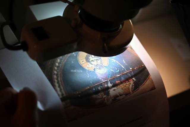 <p>Christina Sotirakoglou a handwriting expert, observes Byzantine paintings based on photographs prints</p>