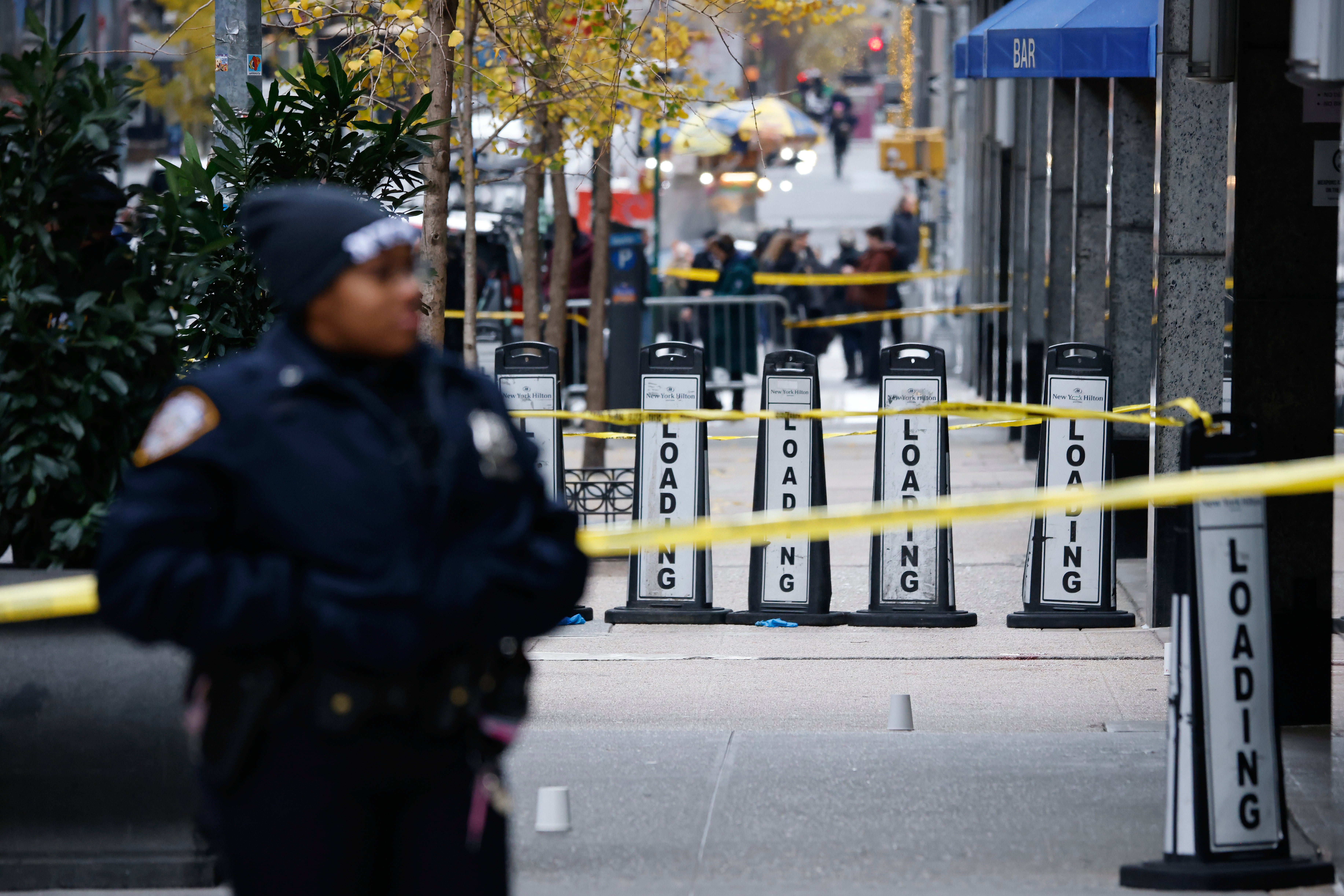 An officer with the New York Police Department stands near the Hilton Hotel in Manhattan where Brian Thompson was fatally shot