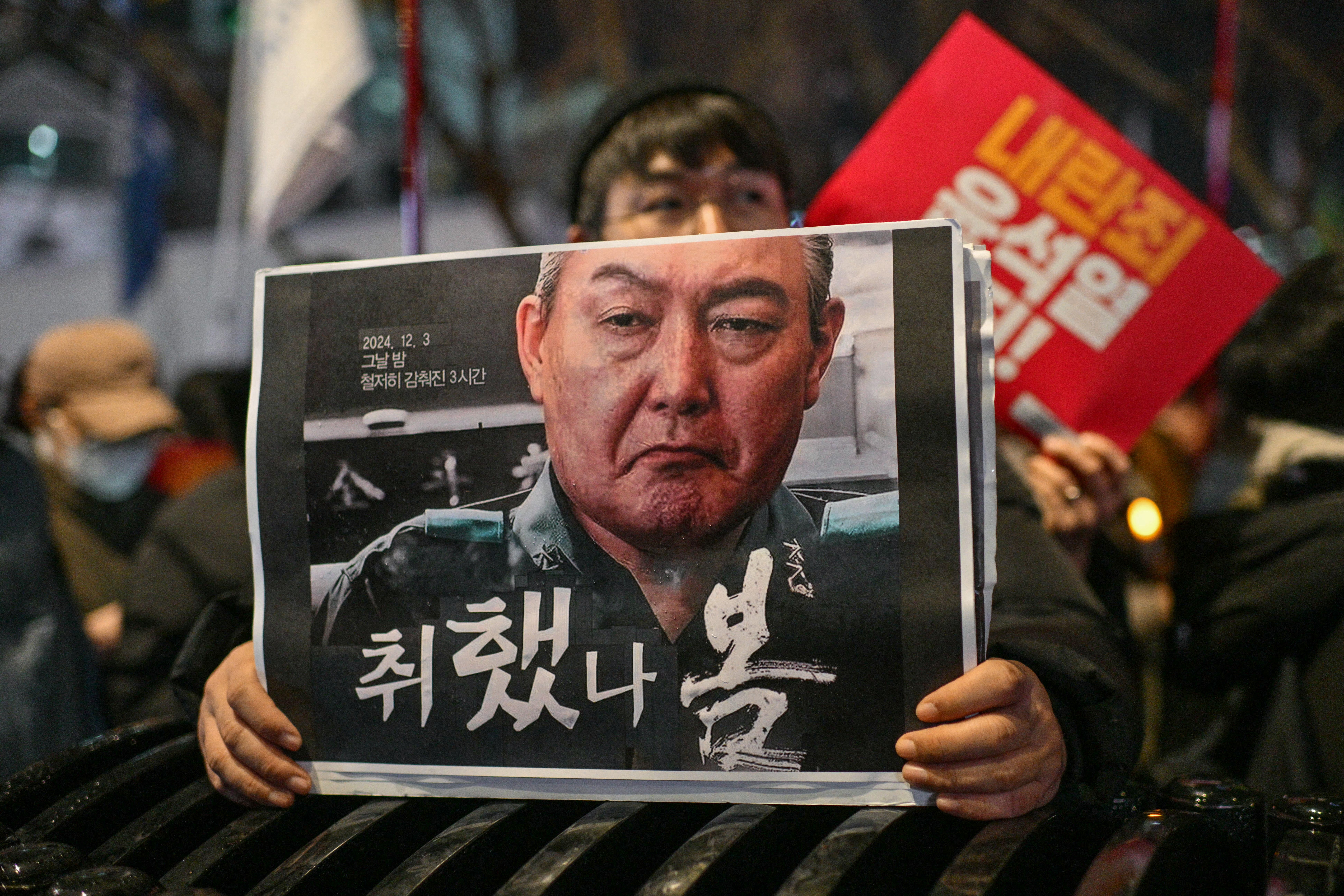 A protester holds a poster with an image of South Korea president Yoon Suk Yeol during a candlelight rally calling for his ouster in Seoul on 5 December 2024