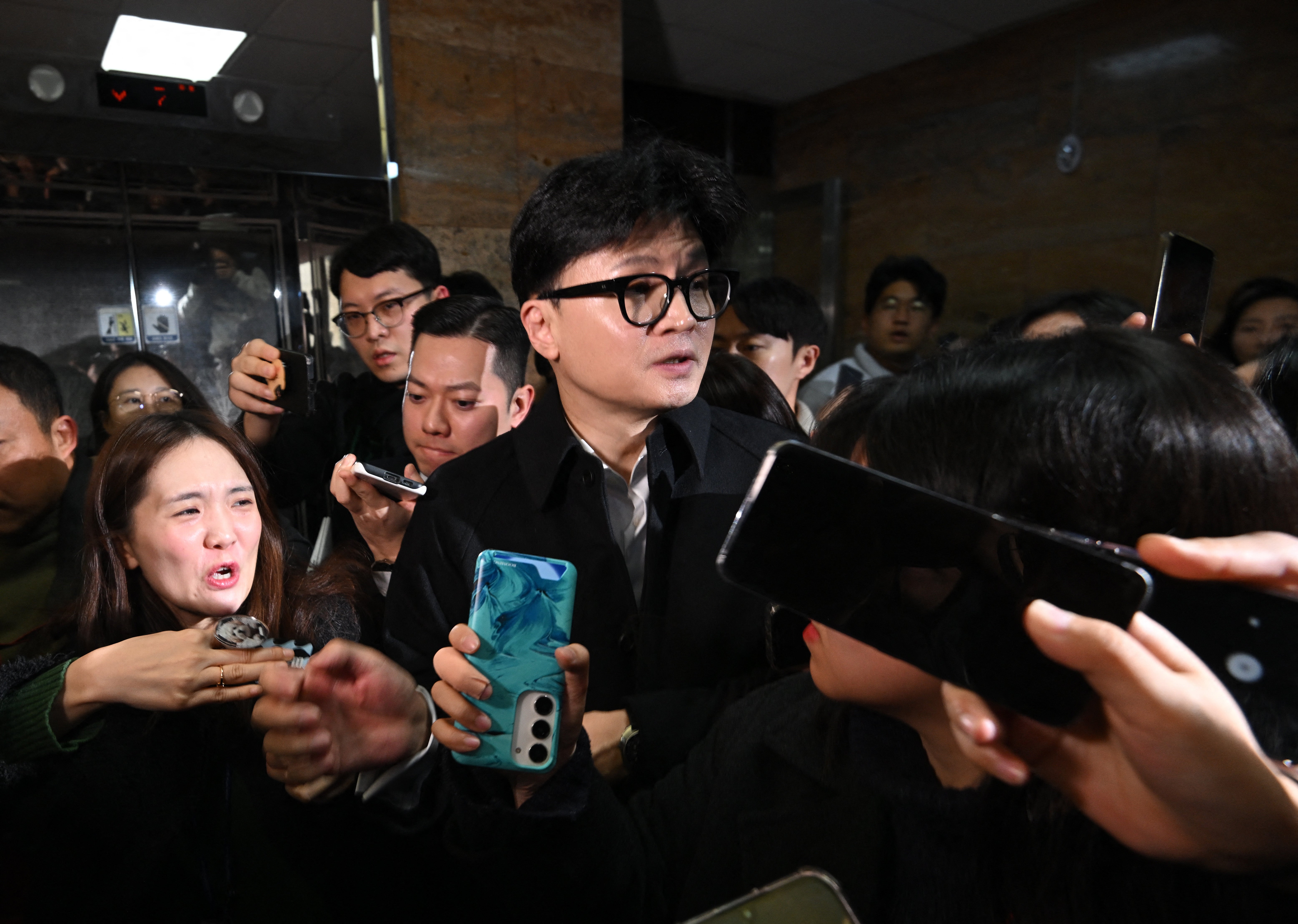 People Power Party leader Han Dong Hoon is surrounded by reporters as he leaves his room at the National Assembly in Seoul on 6 December 2024