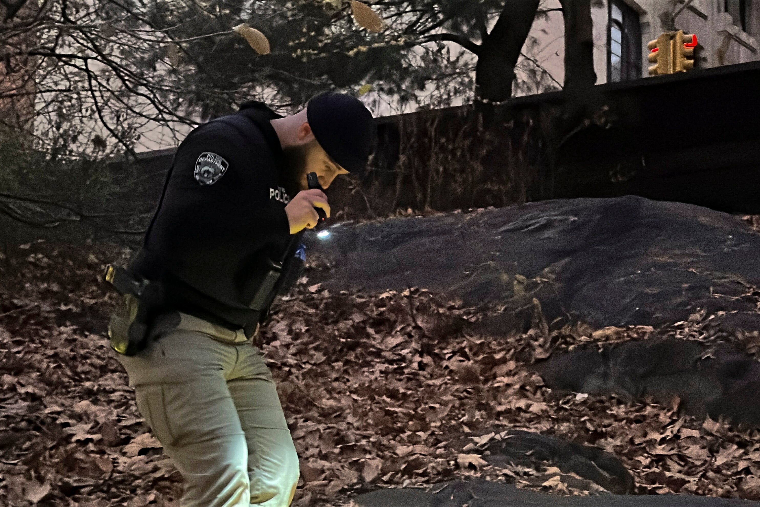 A New York City Police officer walks through brush and foliage in Central Park near 64th Street and Central Park West, Friday, Dec. 6, 2024, in New York, while searching for a backpack police believe was dropped in the park by the person suspected of killing UnitedHealthcare CEO Brian Thompson on Wednesday, Dec. 4, 2024