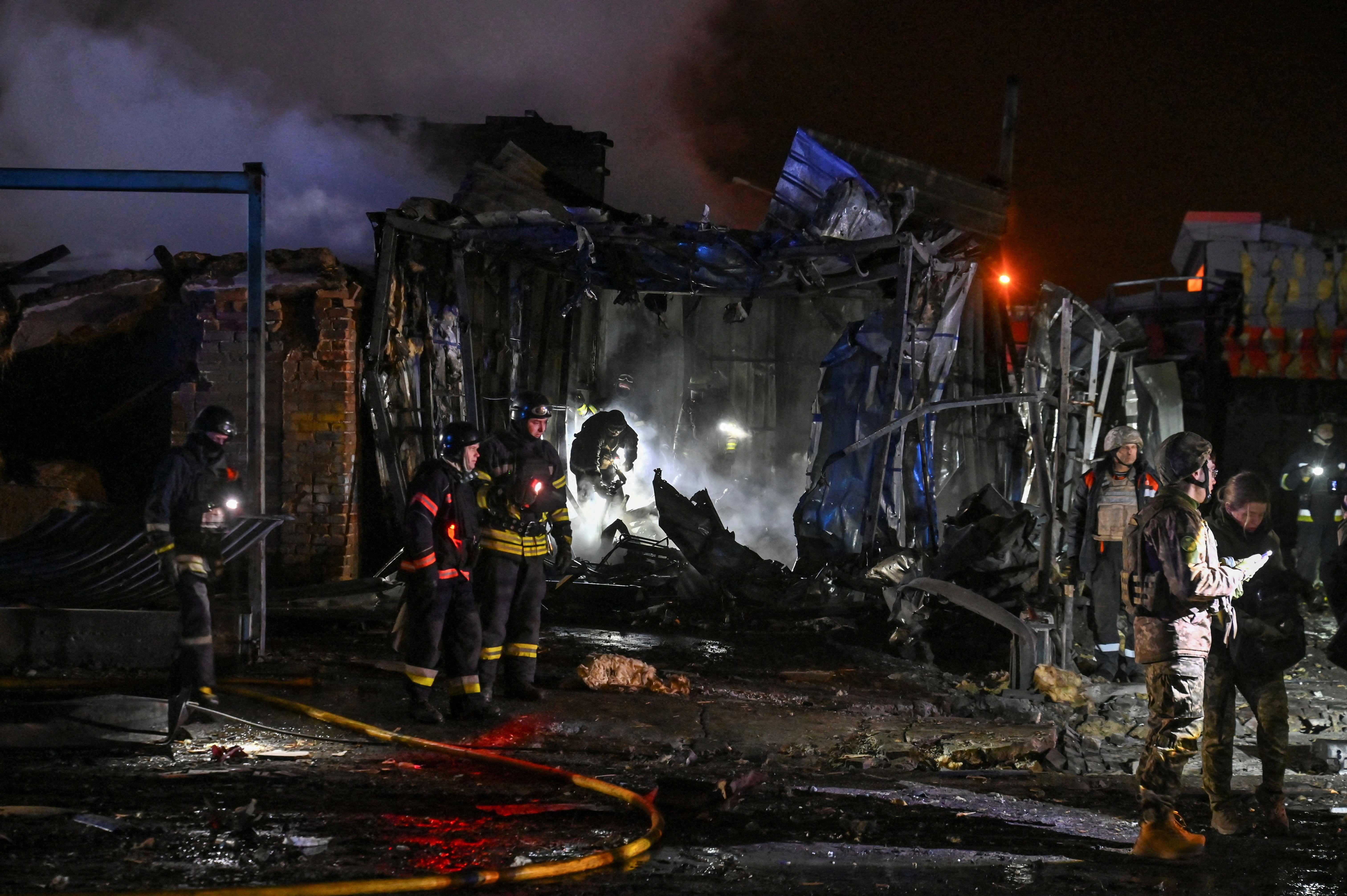 Firefighters work at the site of a car maintenance workshop heavily damaged by a Russian air strike